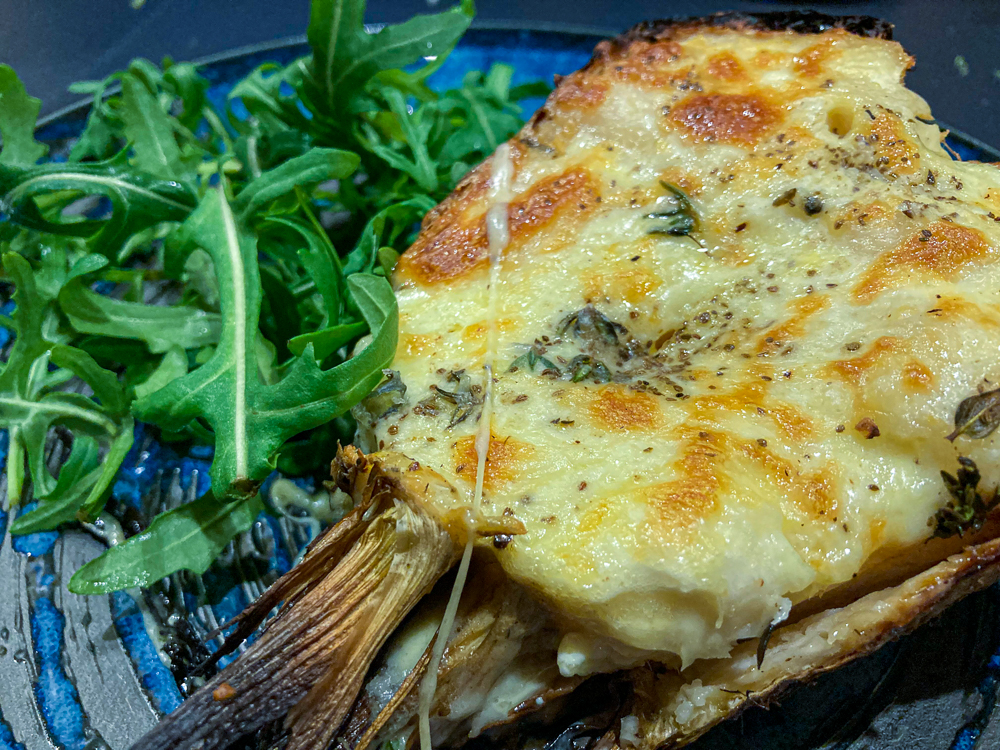 Baked celeriac topped with cheese and served with rocket leaves