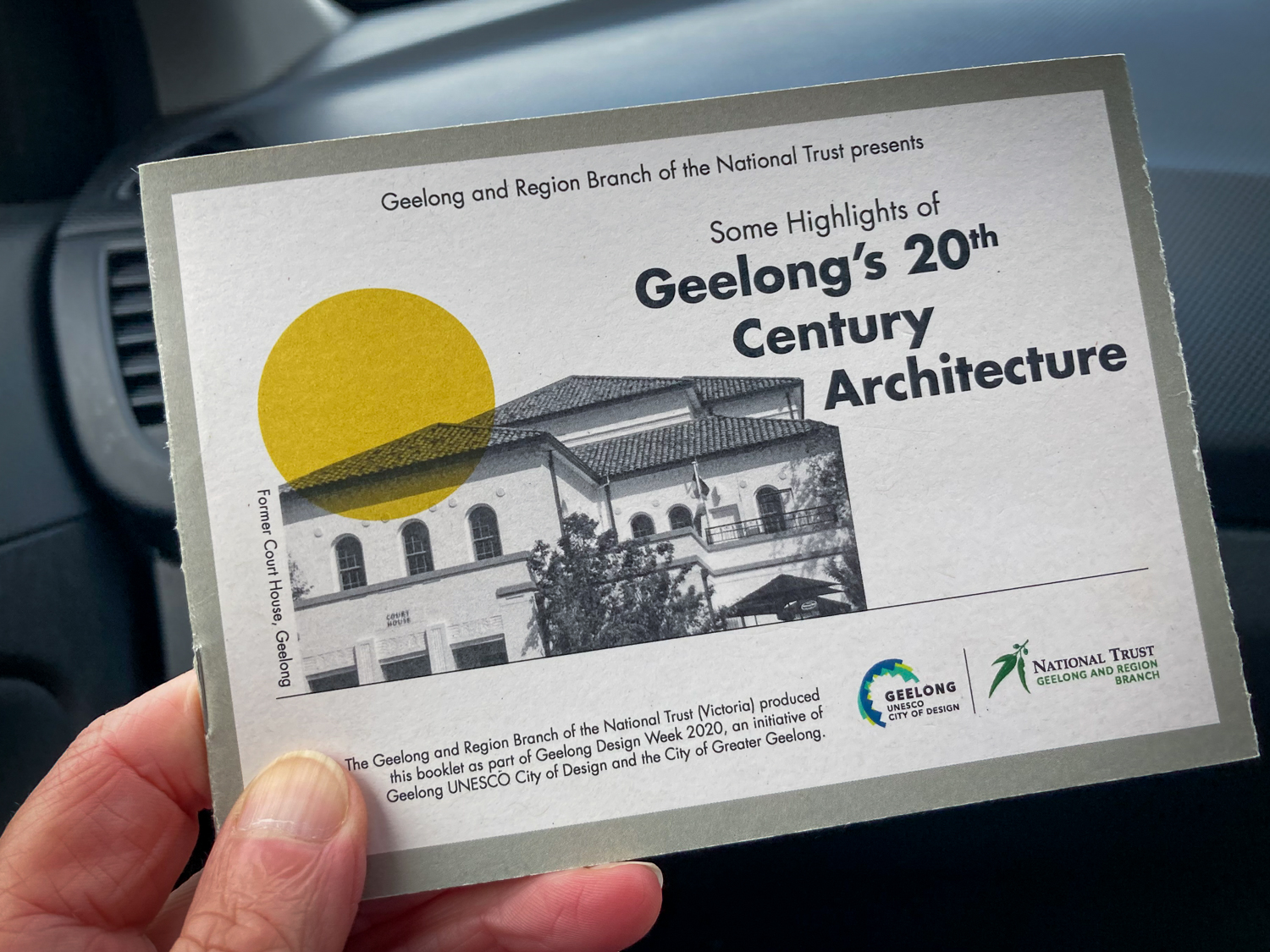 A hand holding a small booklet titled "Some Highlights of Geelong's 20th Century Architecture"