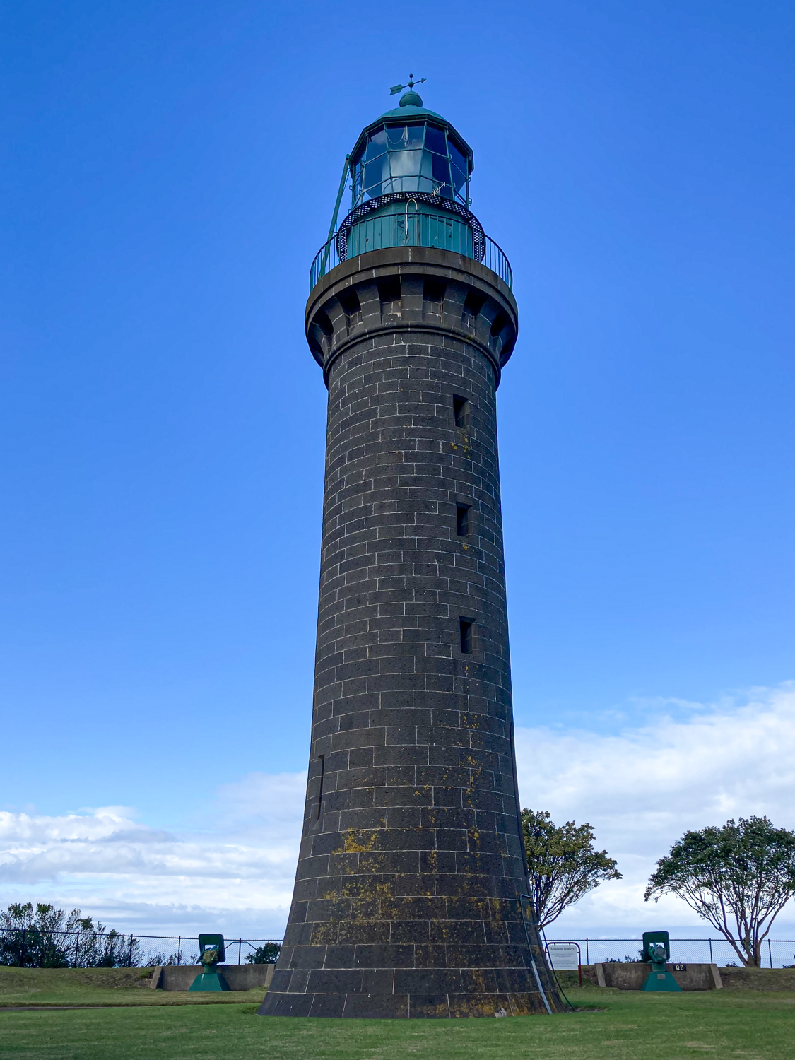 A black lighthouse against a blue sky