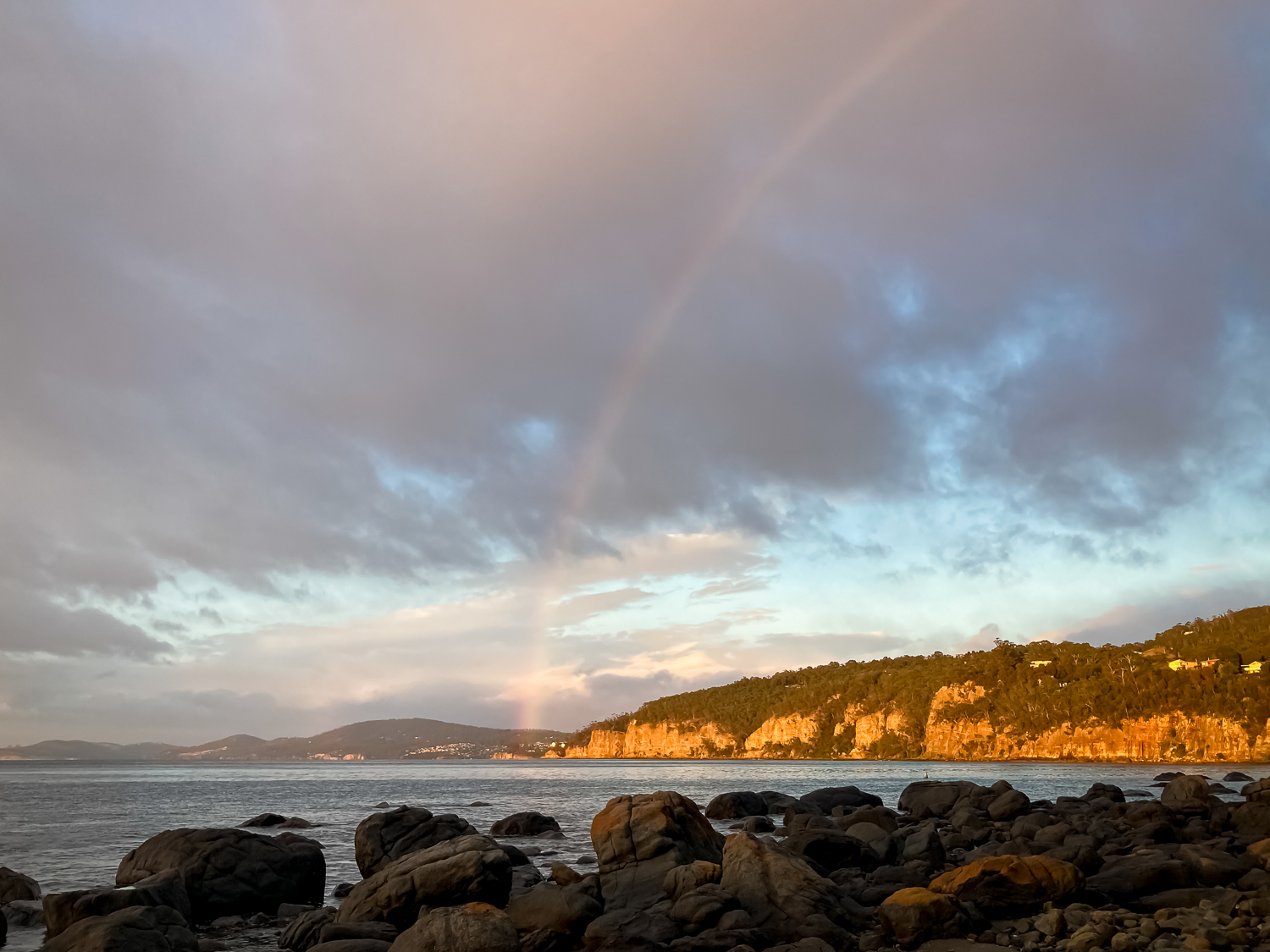 A rainbow over the cliffs at the beach in the morning light