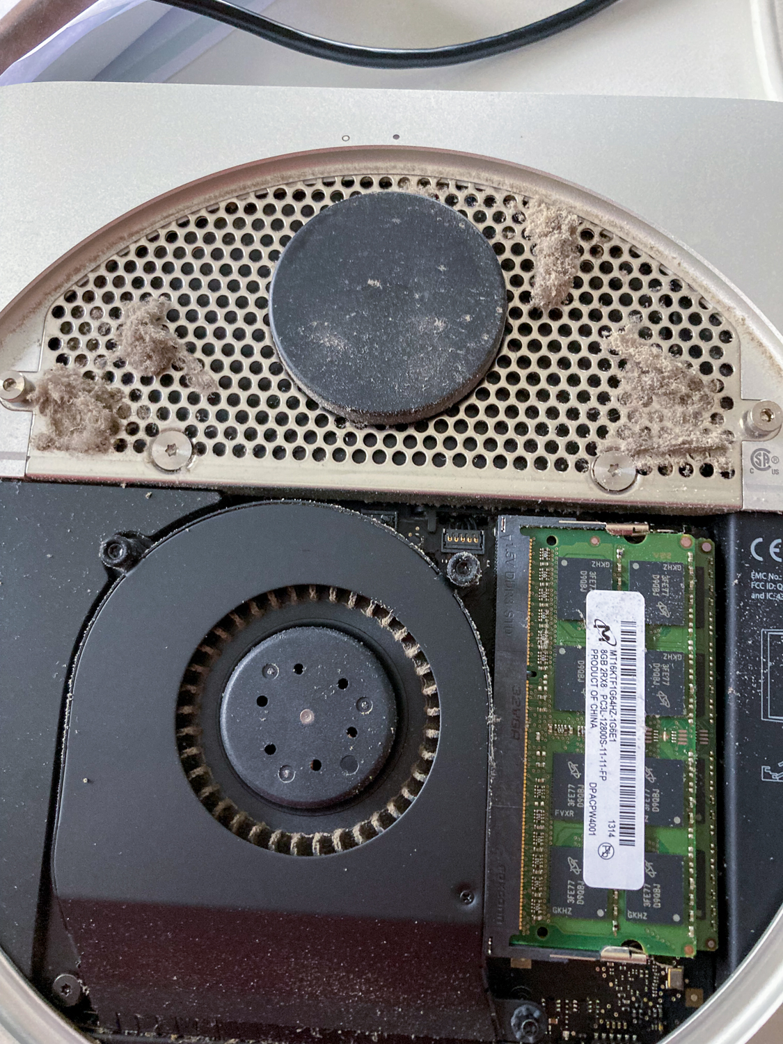 A Mac Mini with the back removed and a lot of dust inside