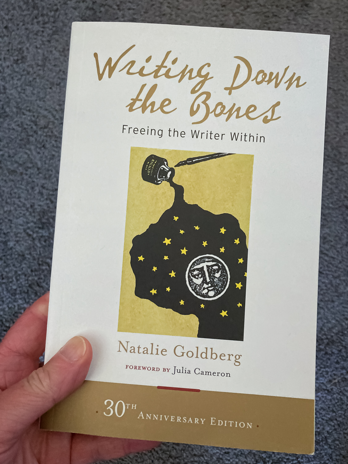 A hand holding the book Writing Down The Bones by Natalie Goldberg