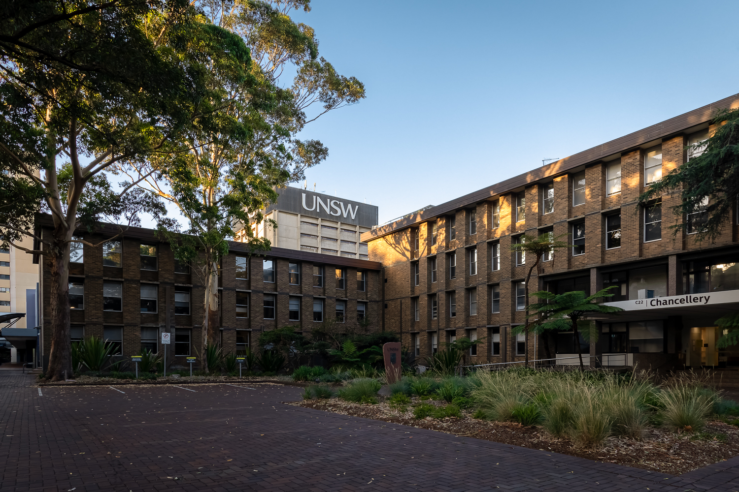 An angled three and four story brick building with a UNSW tower in the background