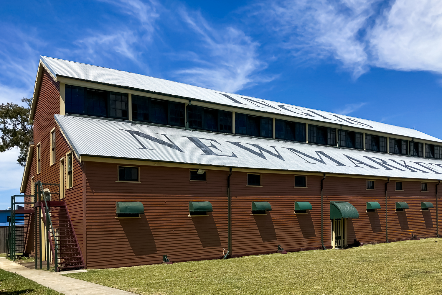 Large painted wooden building with an iron roof and the words INGLIS NEWMARKET on the roof