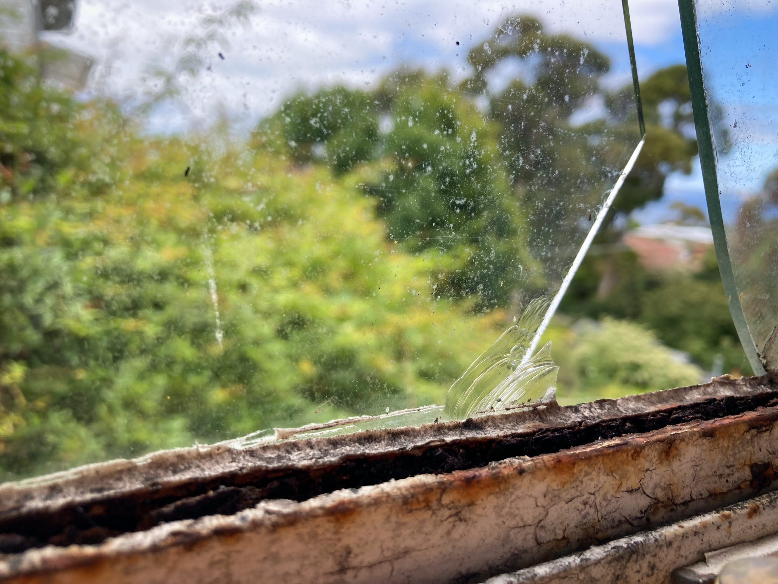 A rusty window frame with a cracked window