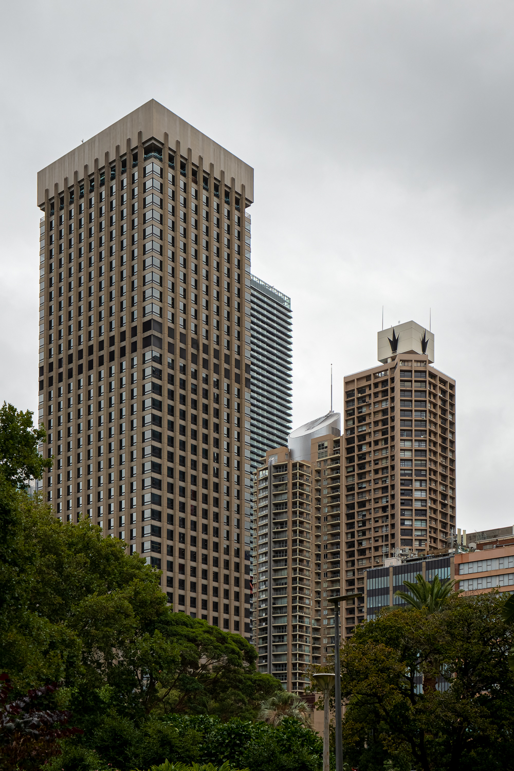 A tall concrete building surrounded by other tall buildings