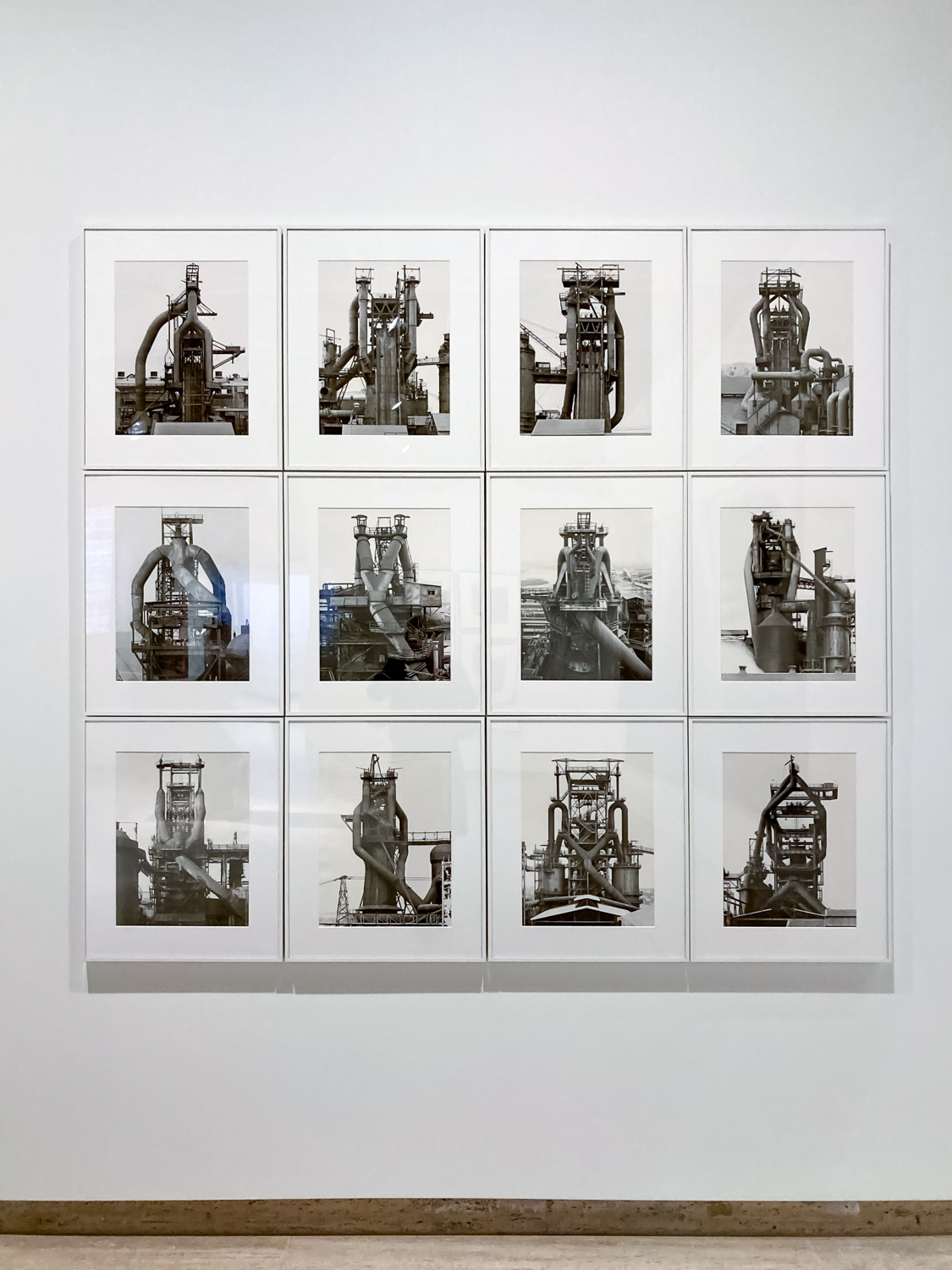three rows of four black and white photos of industrial blast furnaces