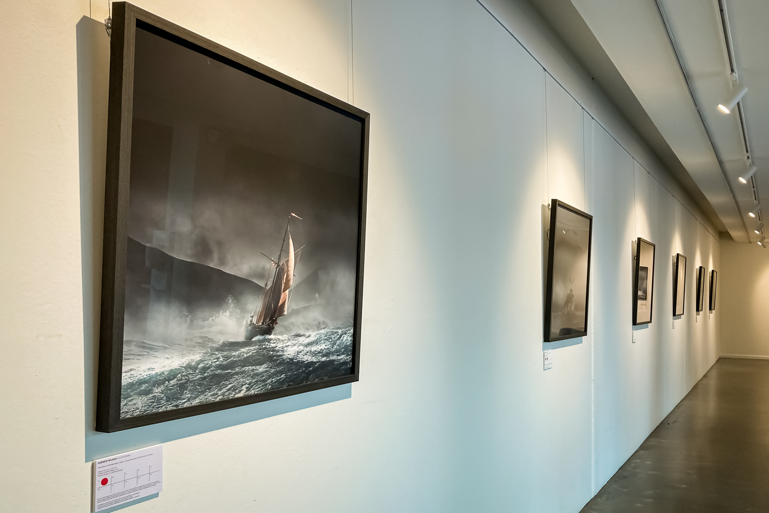 A white gallery wall with a series of maritime images
