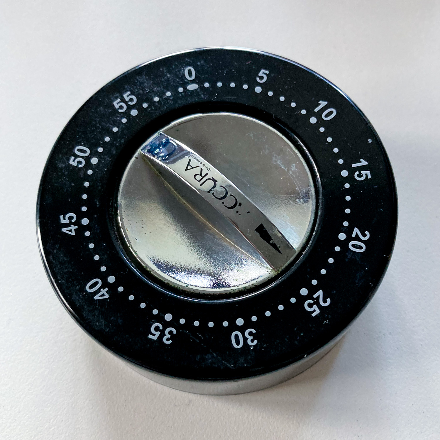 A circular kitchen timer with a black face and silver dial