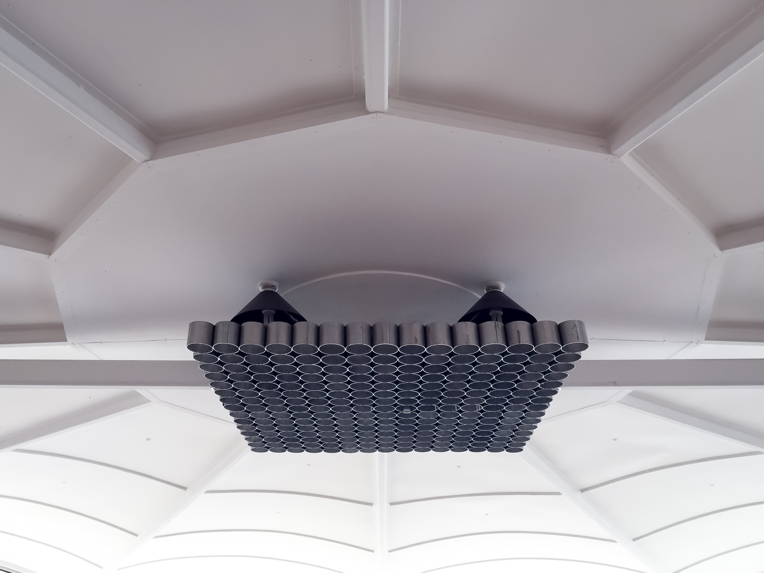 A ceiling with radial lines and a large bank of tubular black lights