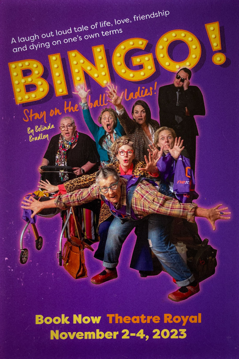 A poster for a play called Bingo! With a cast of six women, and a man dressed in black, on a purple background