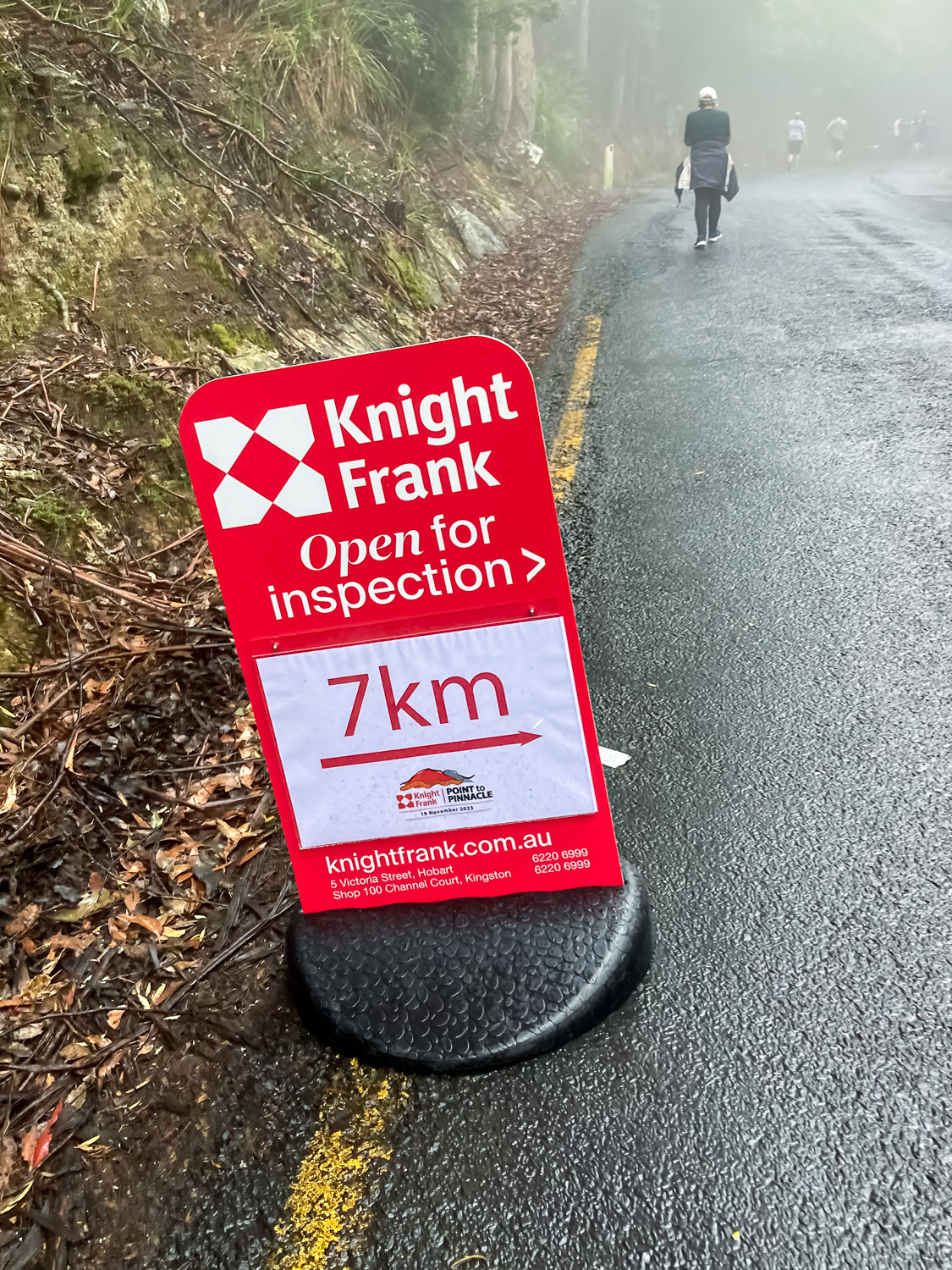 A red sign on the side of a road reading "Knight Frank 7 km"