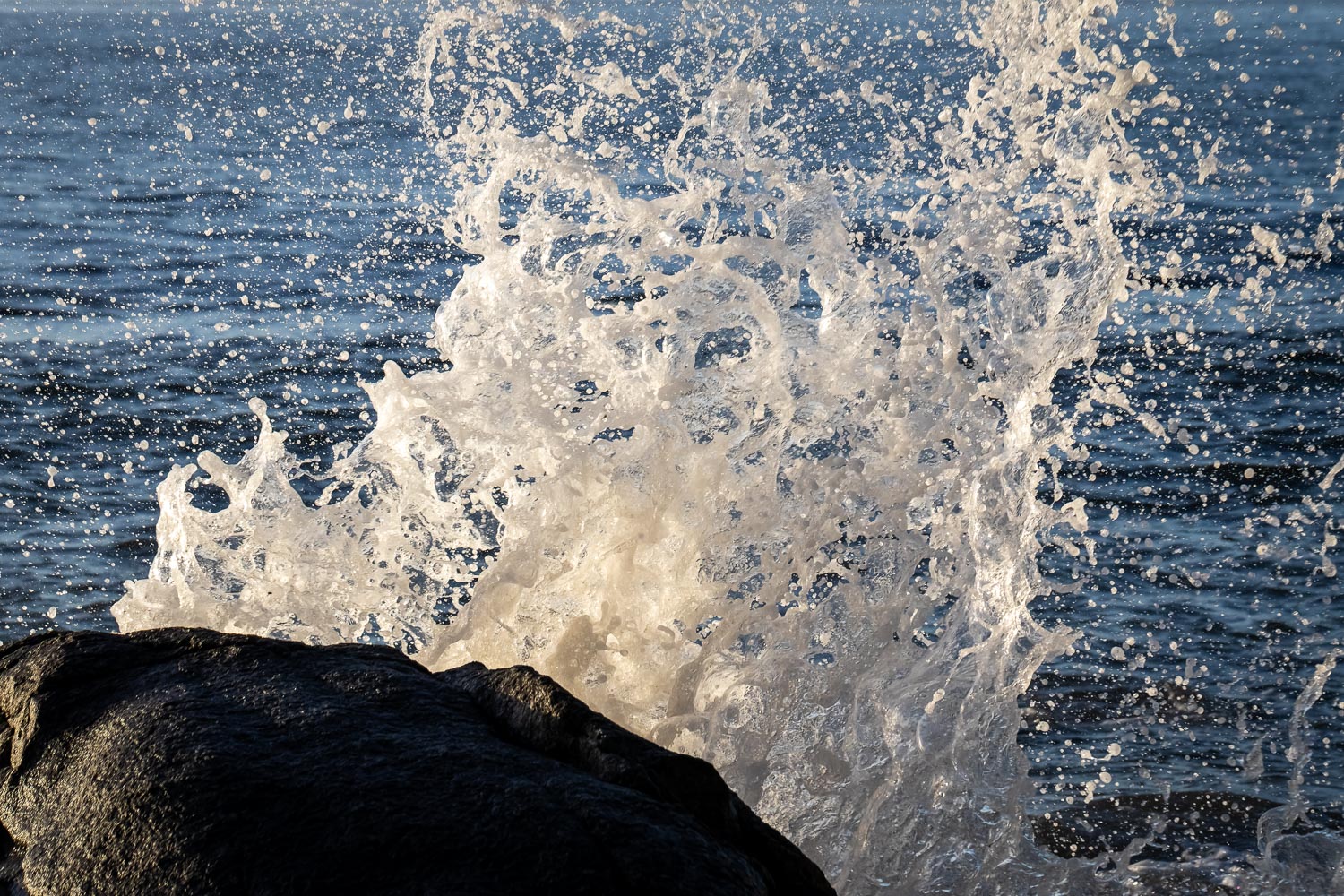 A wave splashing over a rock