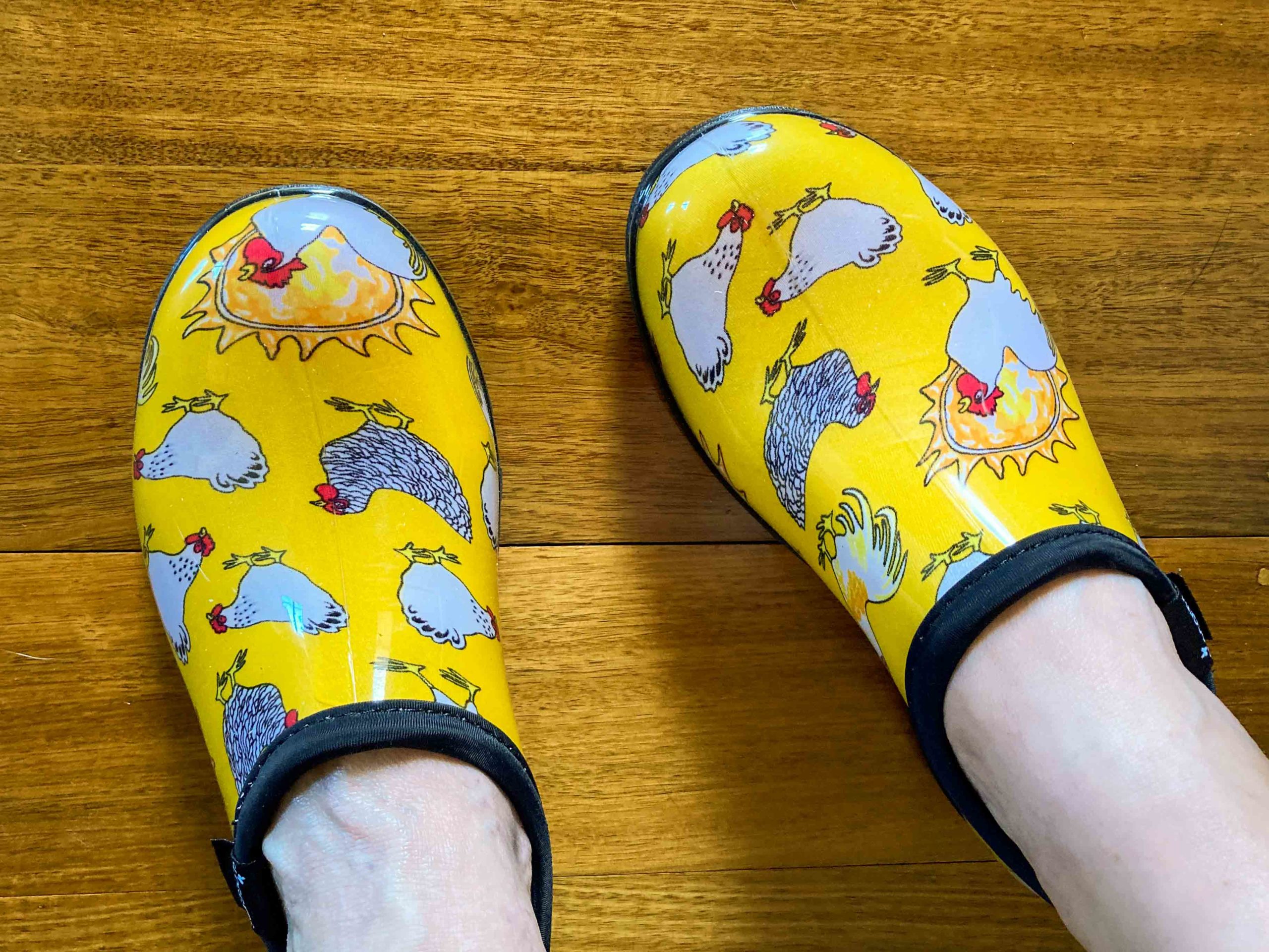 A pair of yellow clog-style shoes with white chicken images