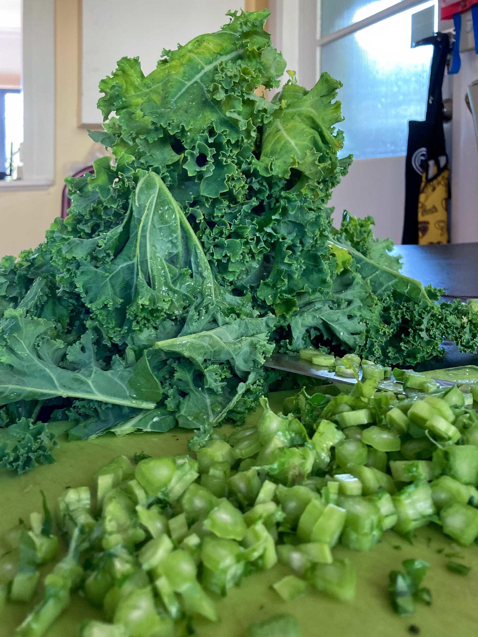 A pile of washed kale leaves, with chopped kale stalks in front of it
