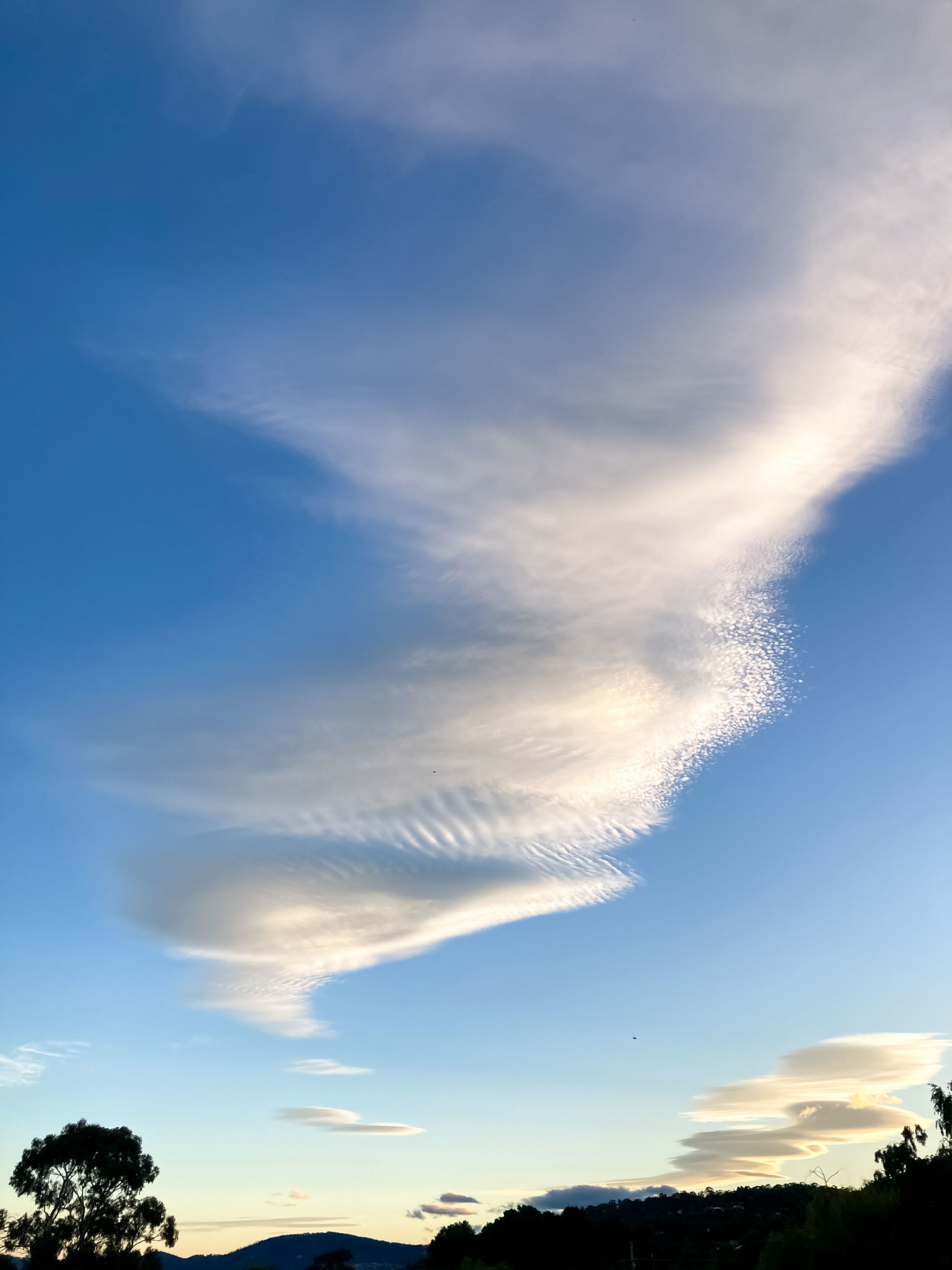 A white, tornado-shaped cloud in a blue sky