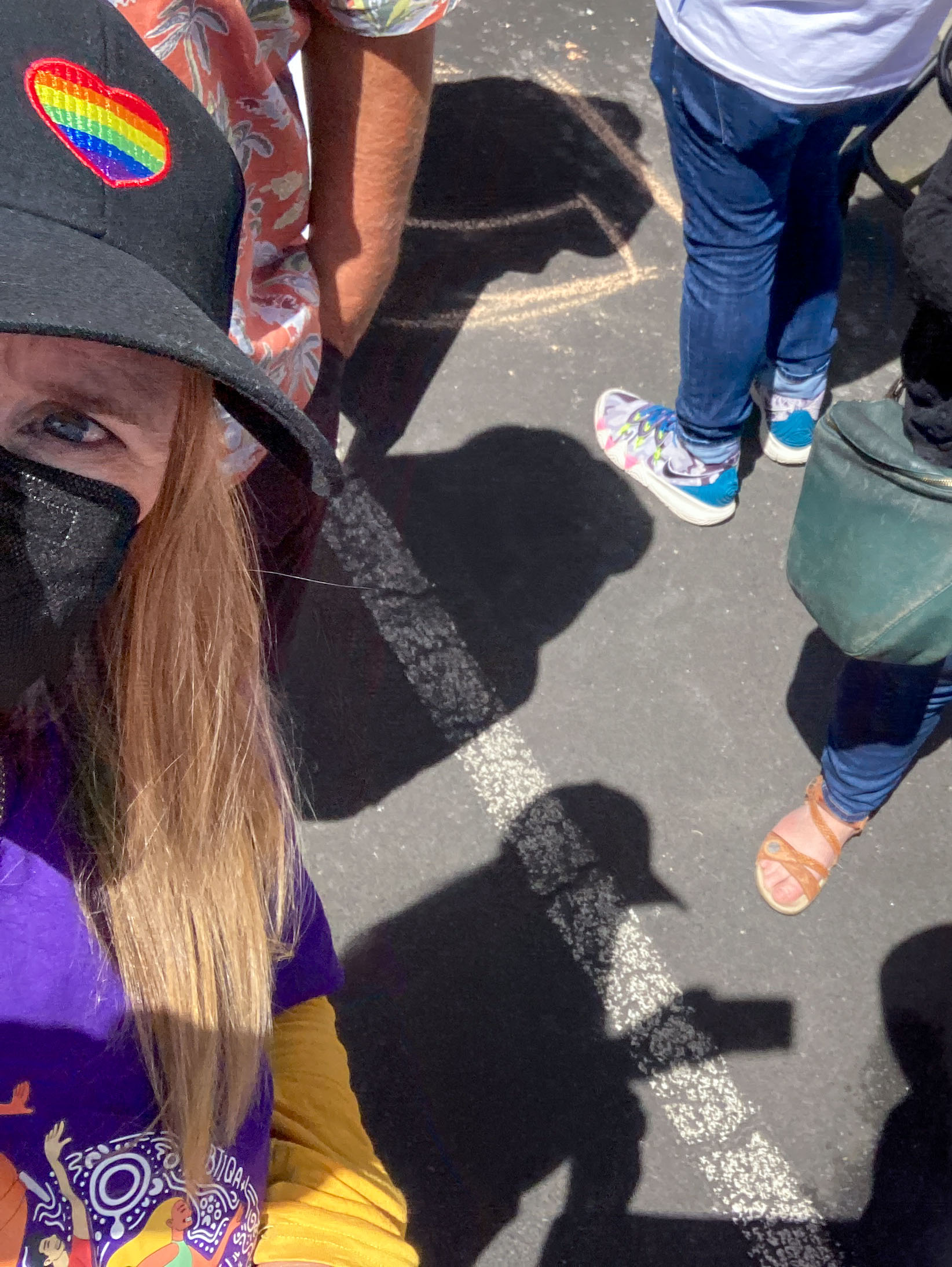 Barb is cut out of most of this photo, half of her is on the left side, she is wearing a cap with a rainbow heart, a black mask and a purple shirt