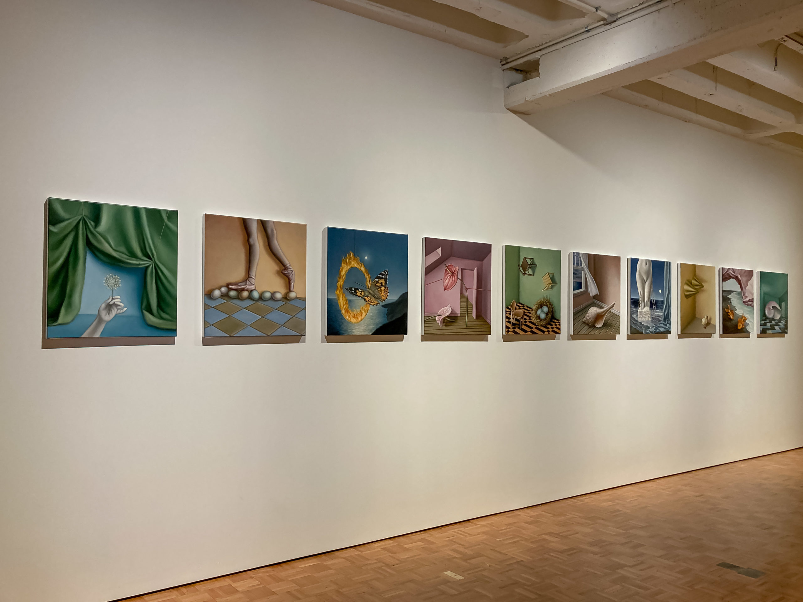 A row of pastel toned paintings hanging on a white wall