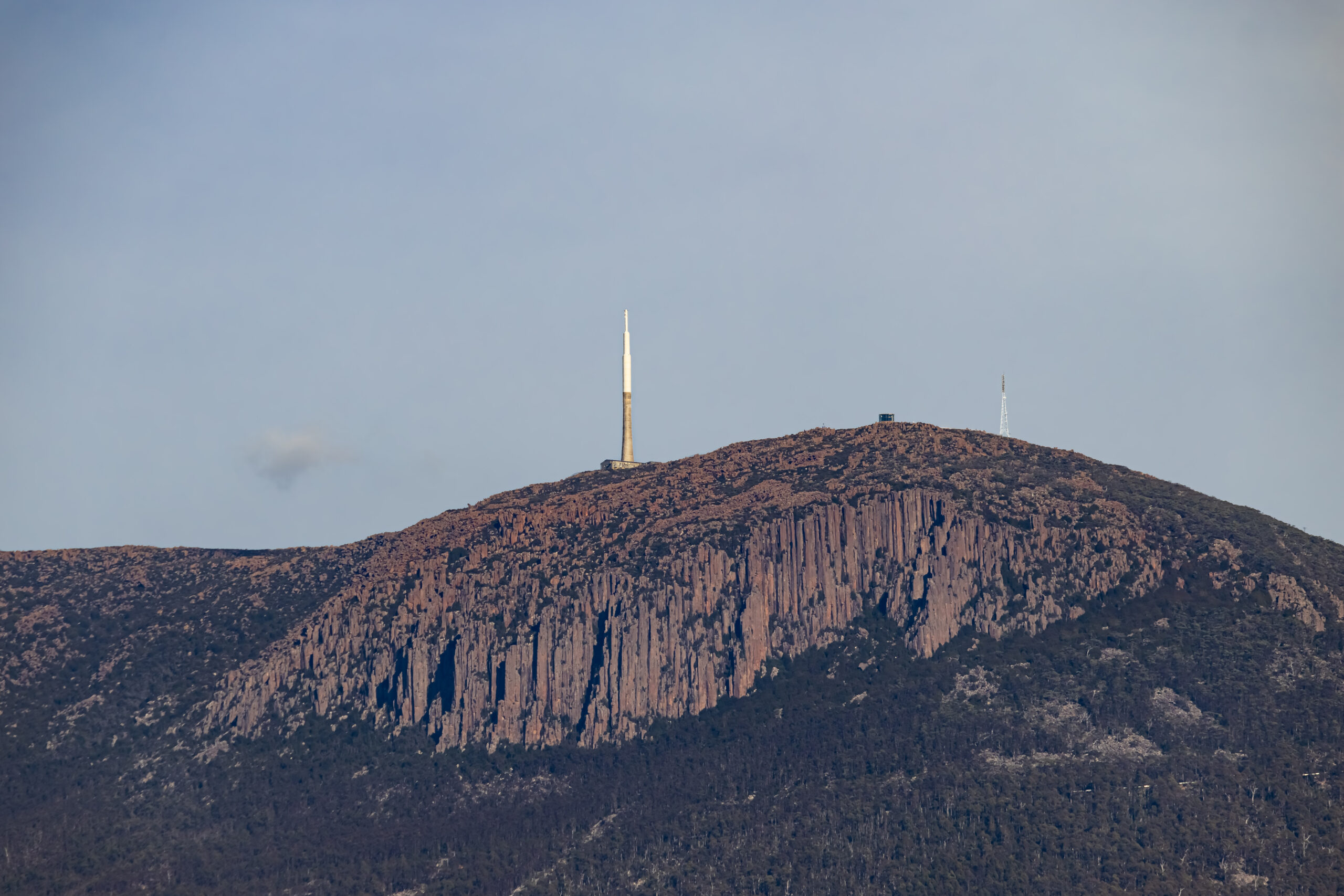 A zoomed in photo of a mountain with a large tower on its summit