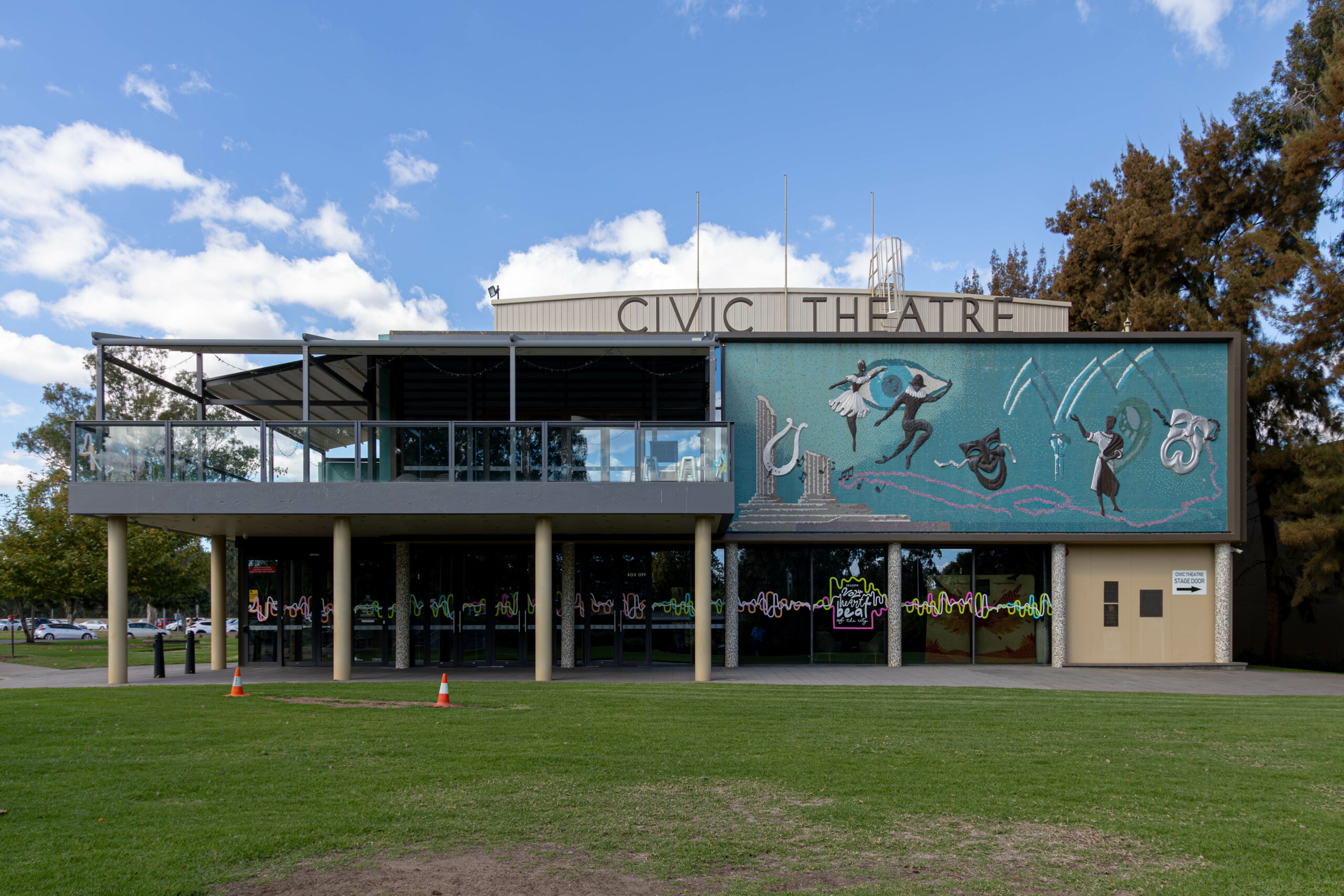 A two-storey modernist building with the words CIVIC THEATRE on top and a bue/green mural on the right hand side
