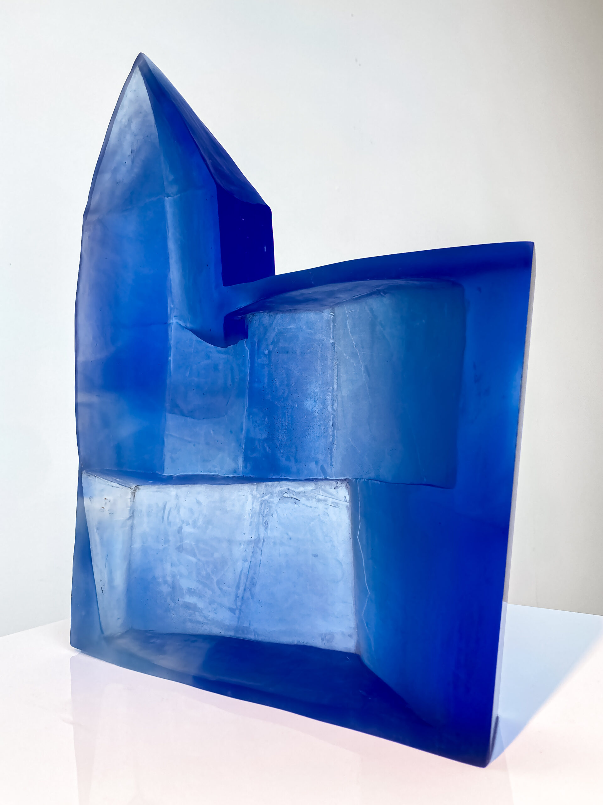 A striking blue cast glass sculpture with many facets and angles