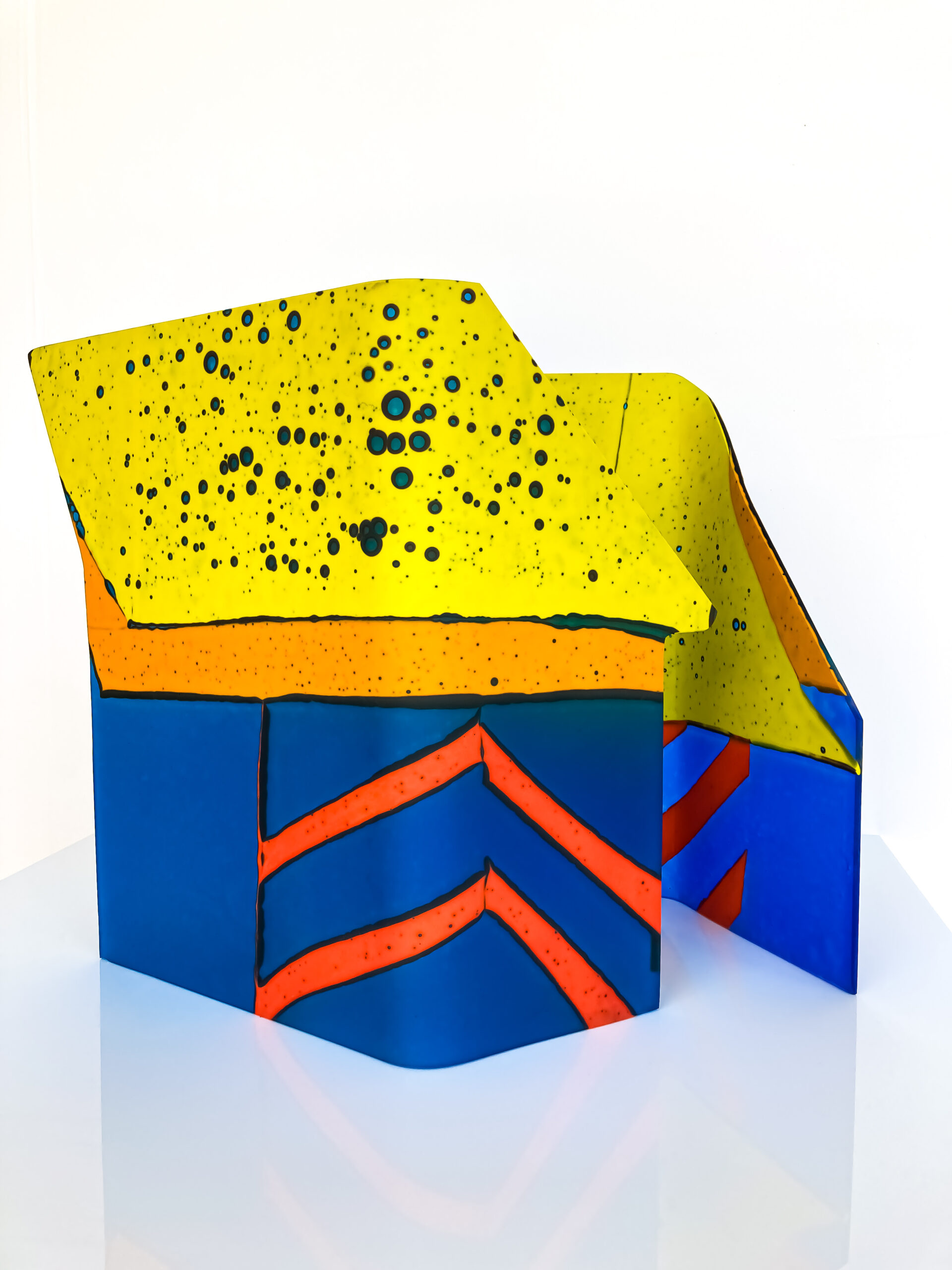 A bold glass sculpture of blue, yellow and orange. It sort of resembles a building
