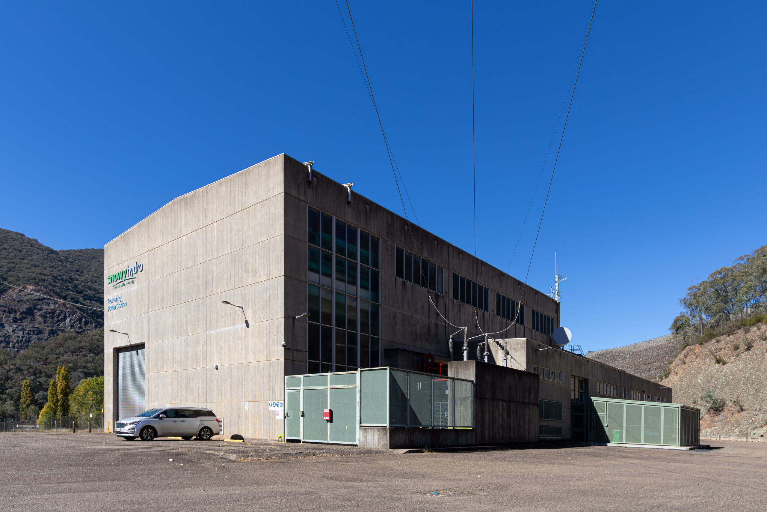 A large three-storey monolithic concrete building surrounded by a green fence