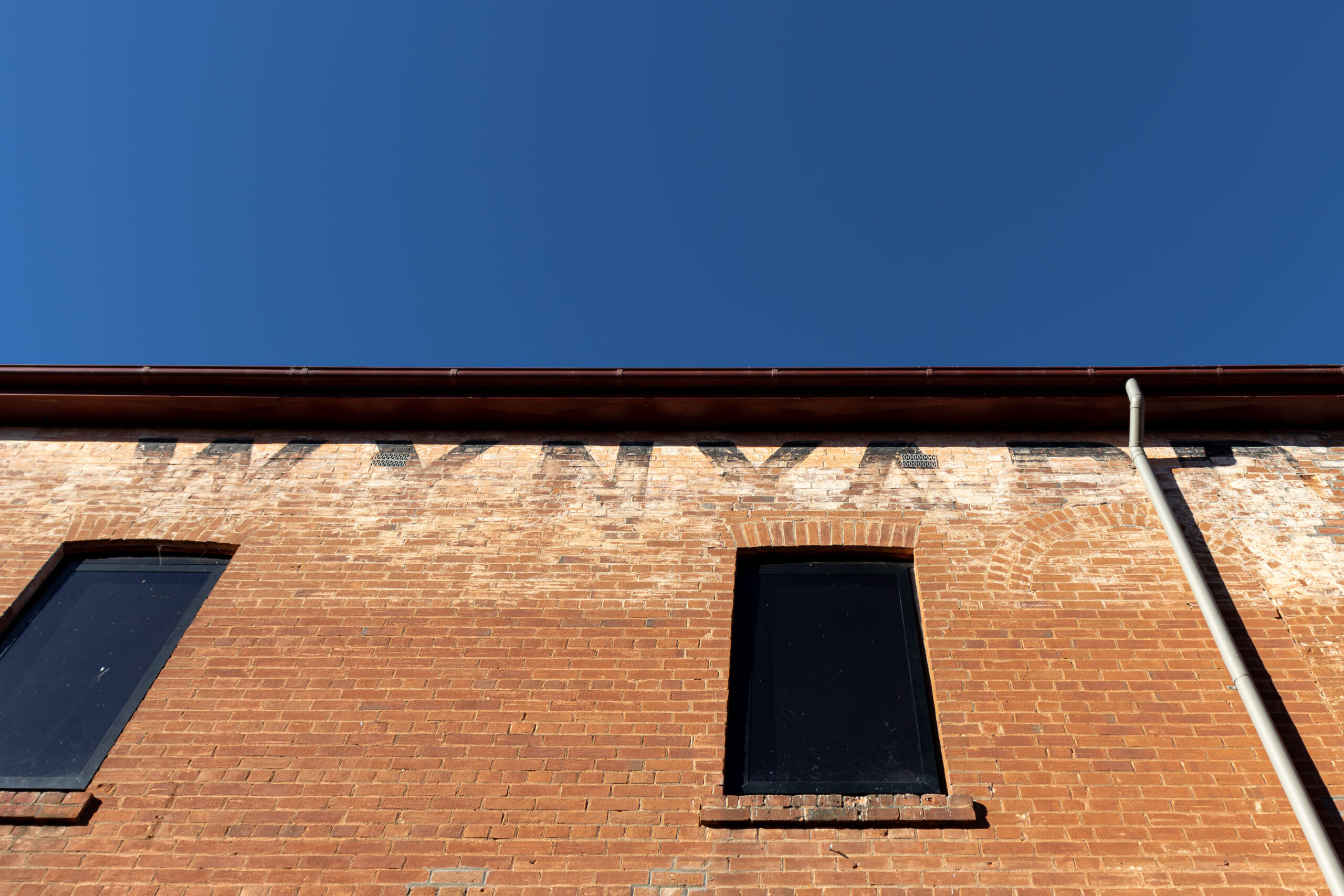 An orange brick wall with faded lettering spelling "Wynyard" at the top