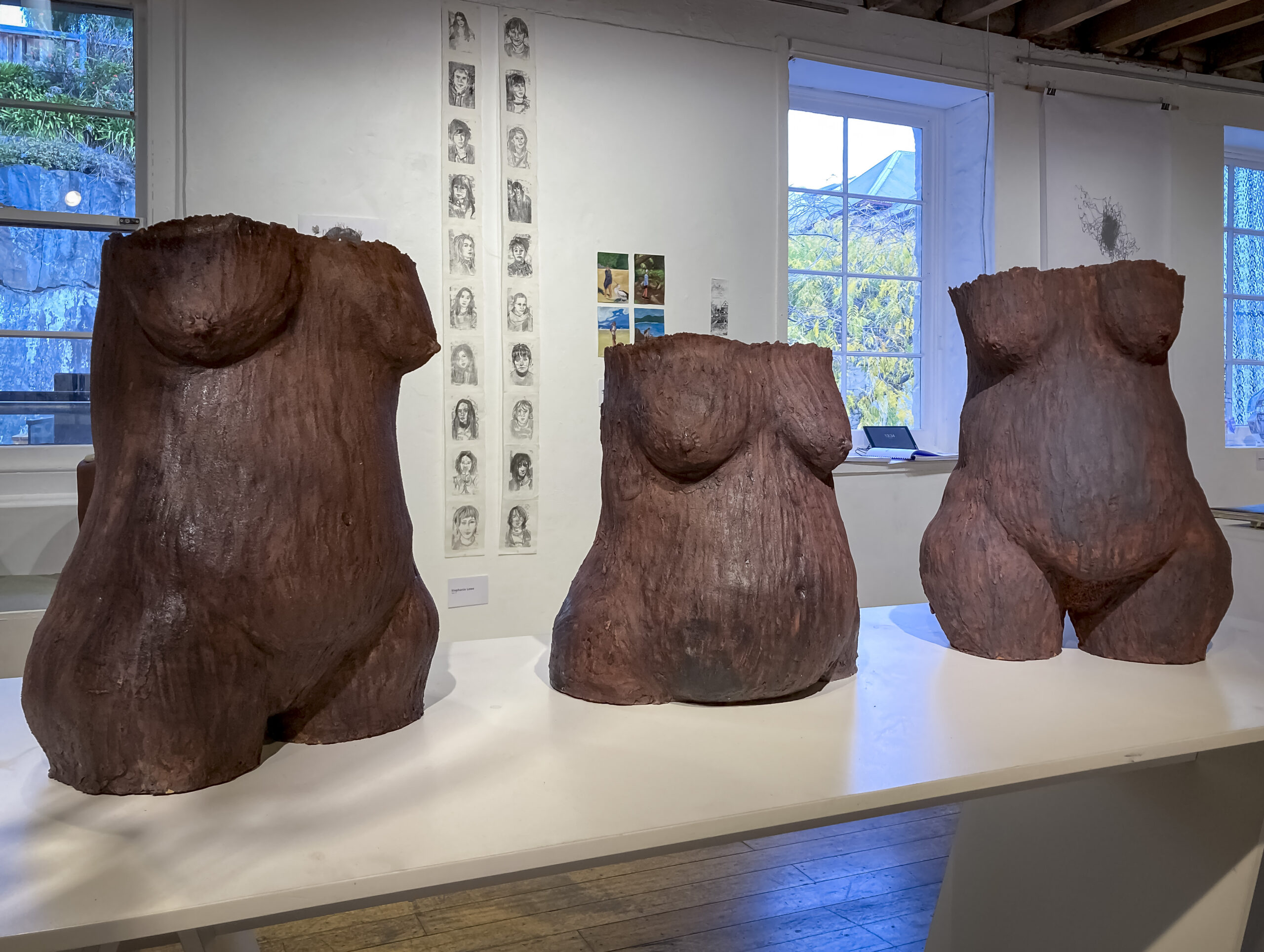 Three female torsos in clay and iron oxide which look like slightly rusted metal