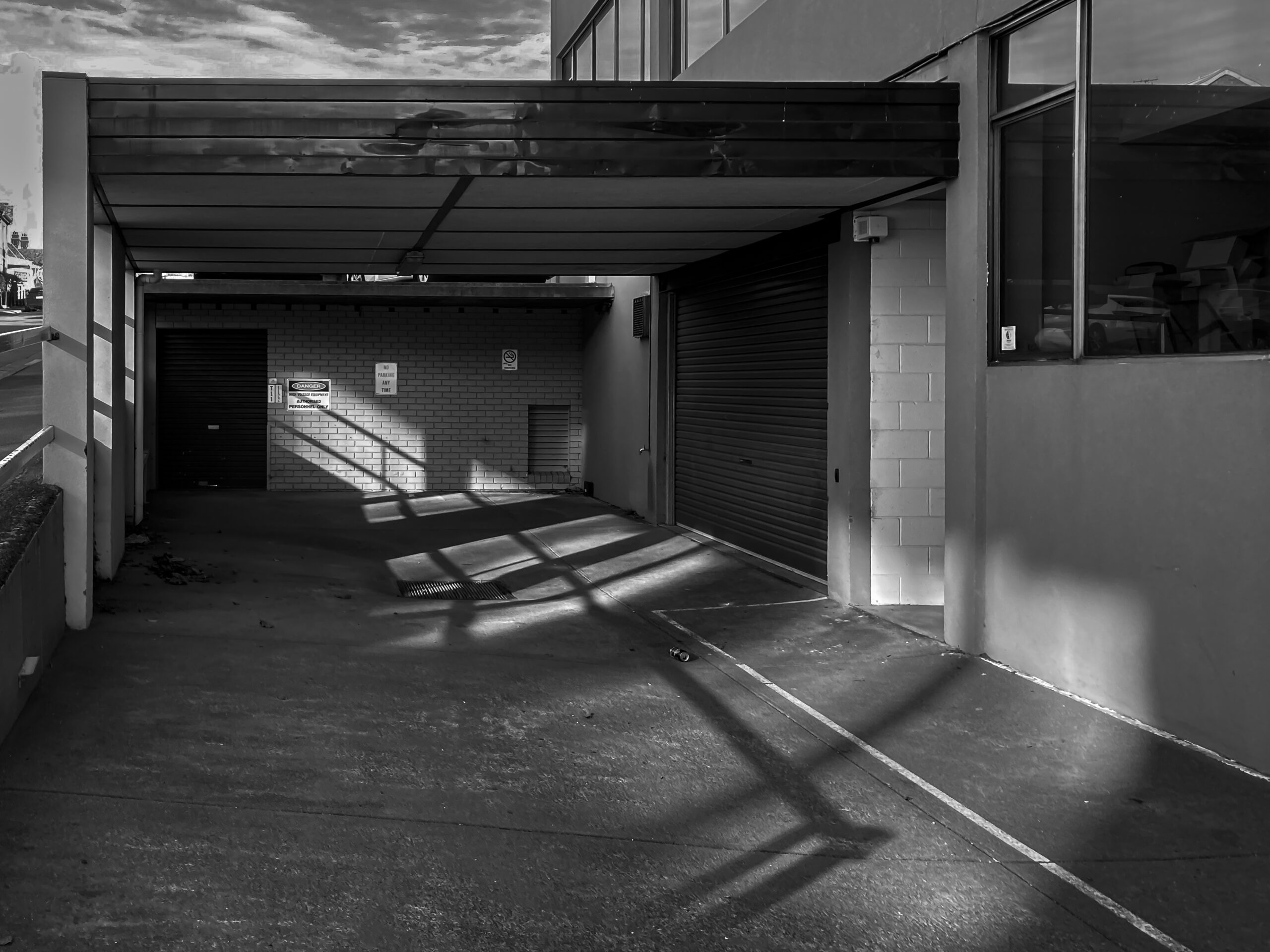 A black & white image of light streaming into a darkened parking garage