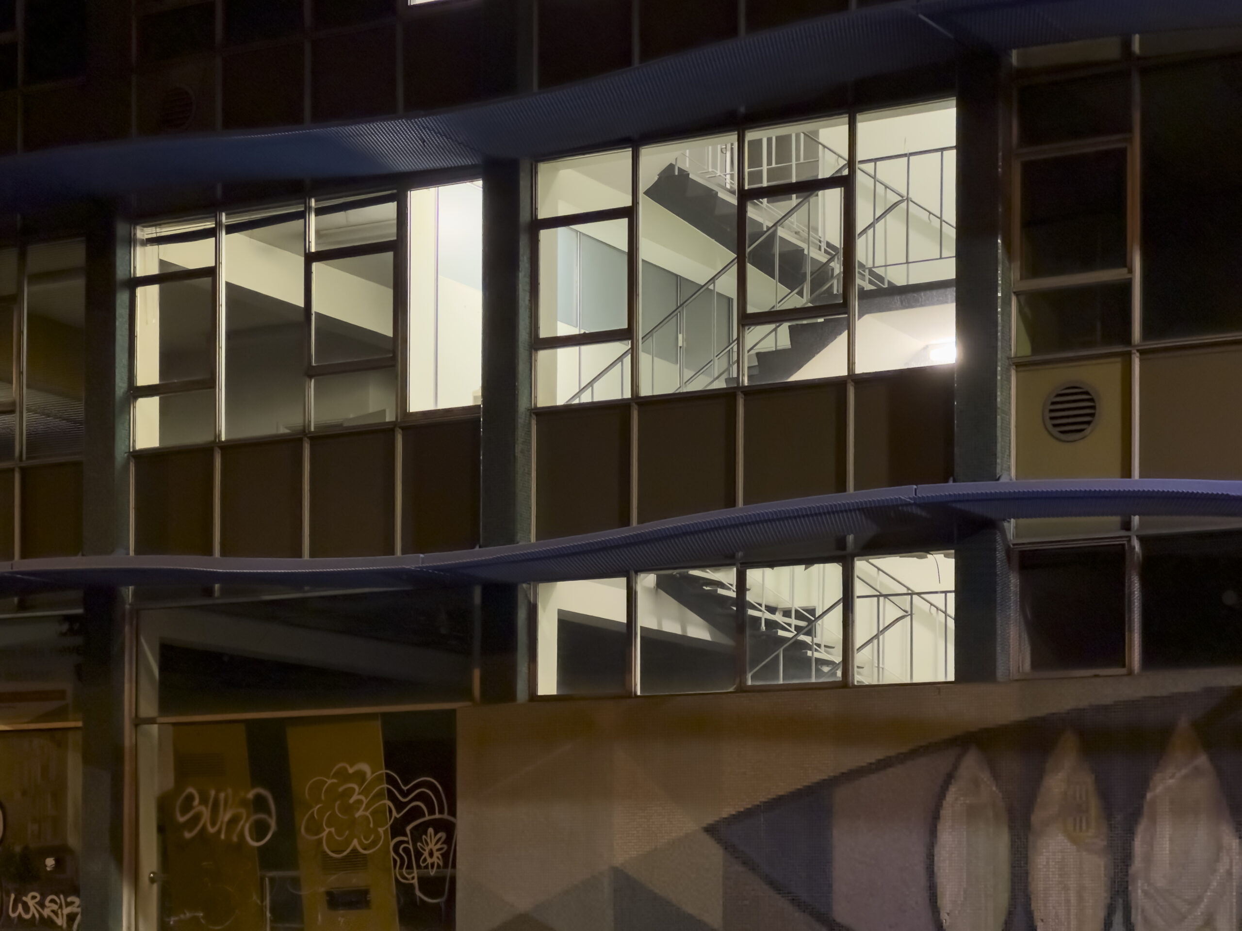 A close-up photo of an empty multistorey building with some lights on inside in the stiarwell