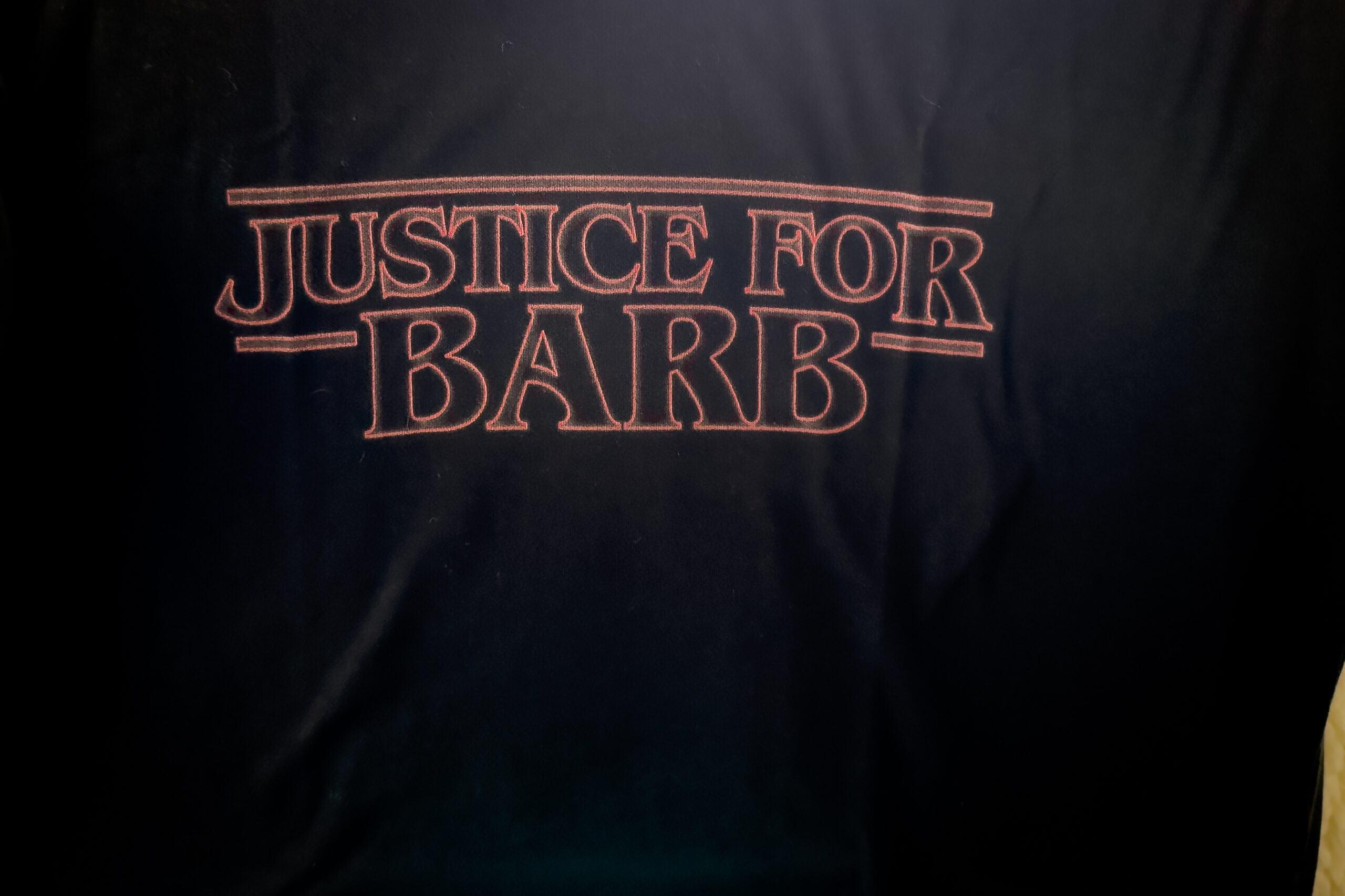 A logo in red text on black fabric with the words JUSTICE FOR BARB