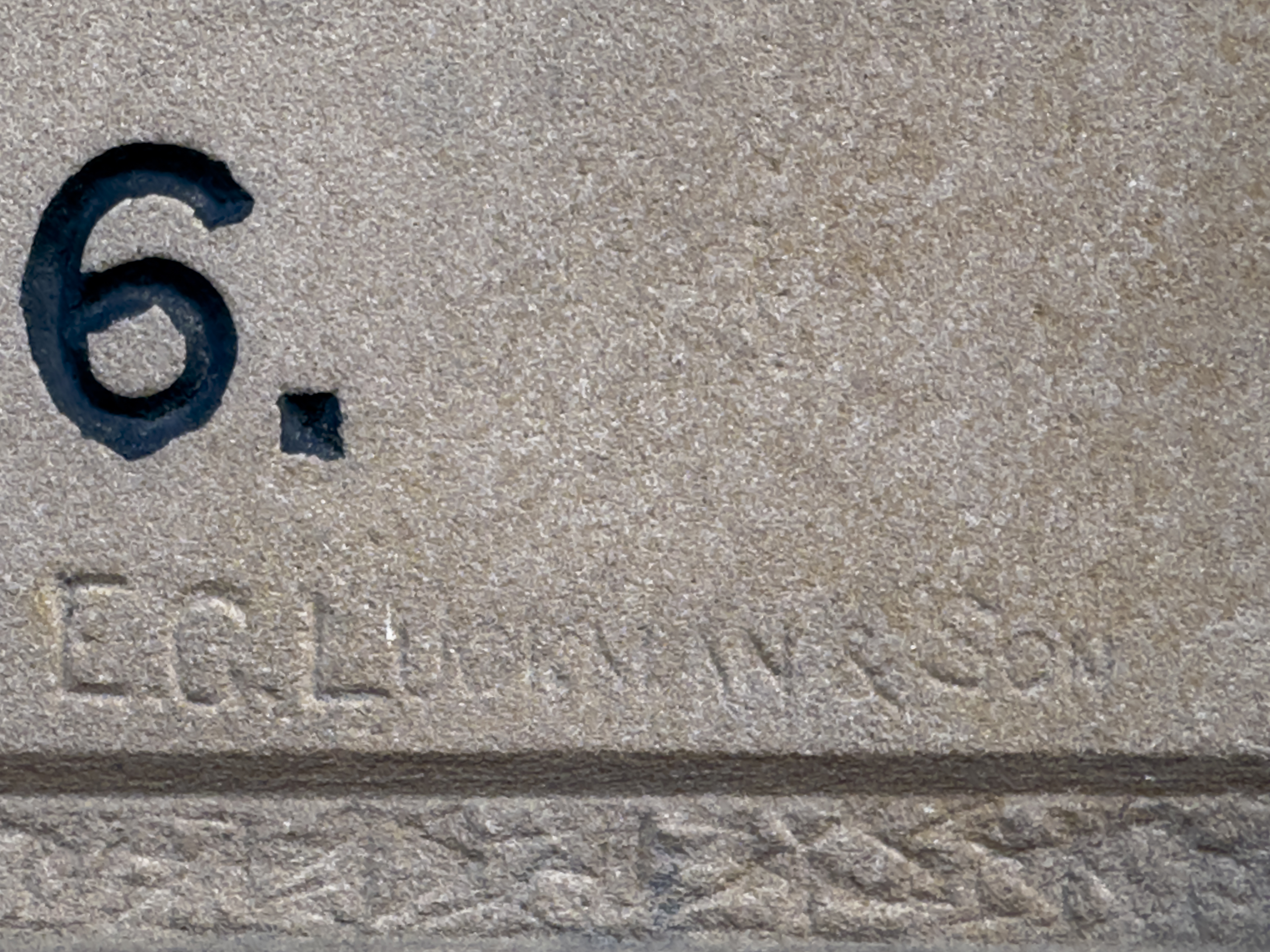 A sandstone block with a larger number 8 in black lettering and carved smaller the words "EG Luckman & Son"