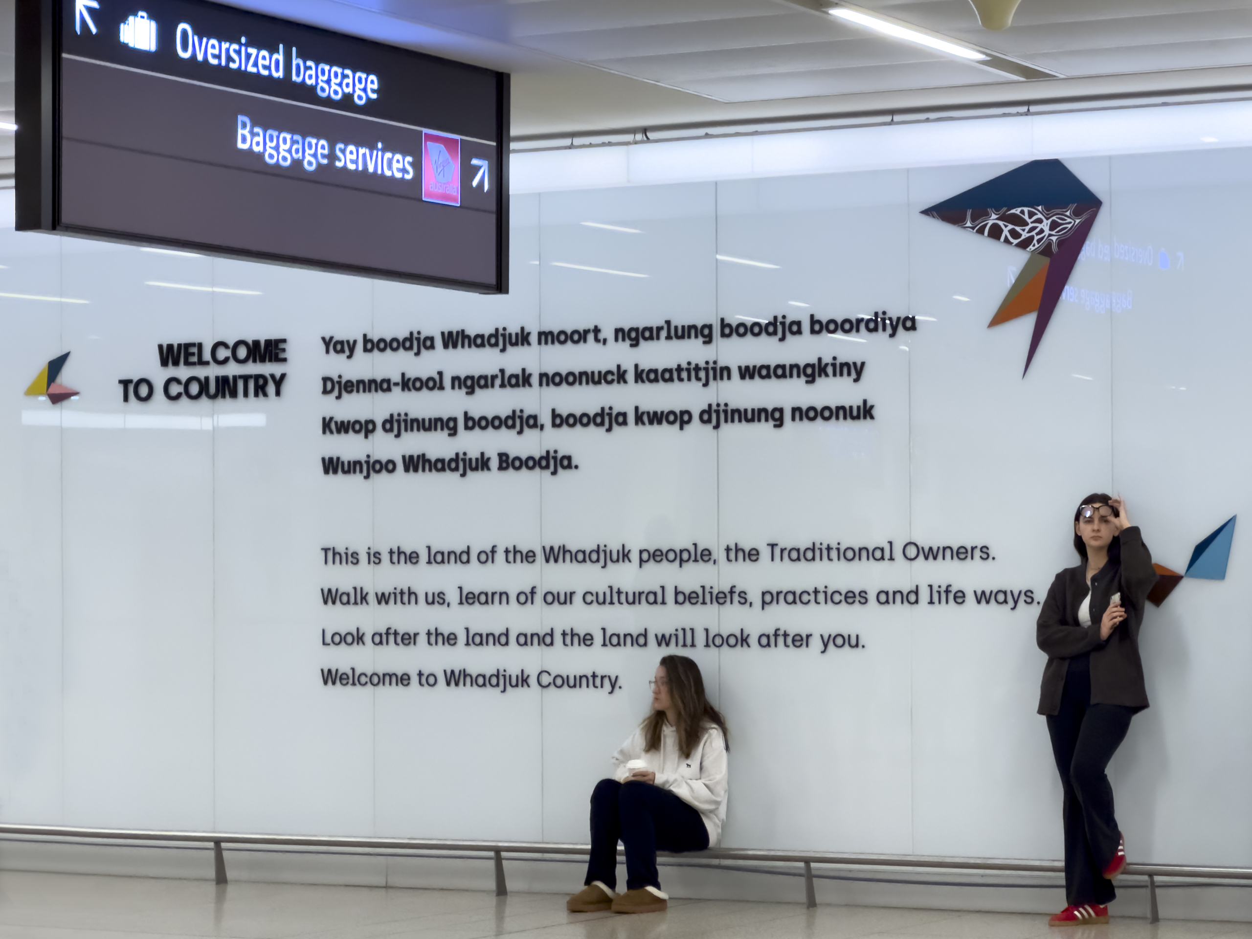 A "Welcome to Country sign" at an airport baggage claim, welcoming travellers to Whadjuk Country.