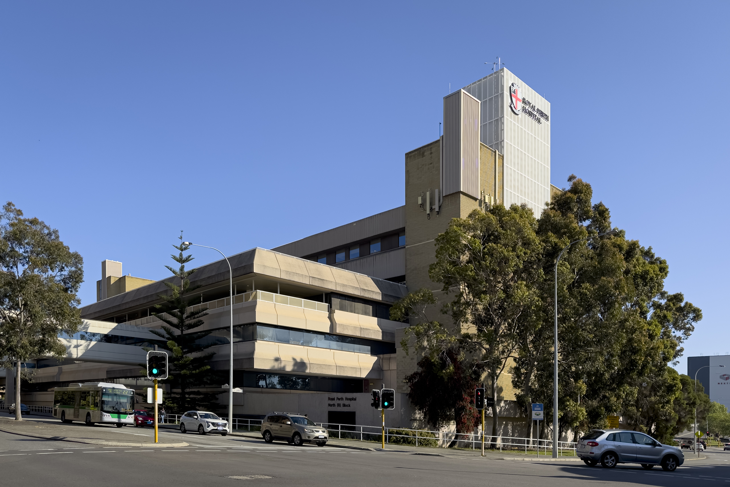 A brutalist style building on a street corner with a smaller section at the front and a slightly larger tower behind