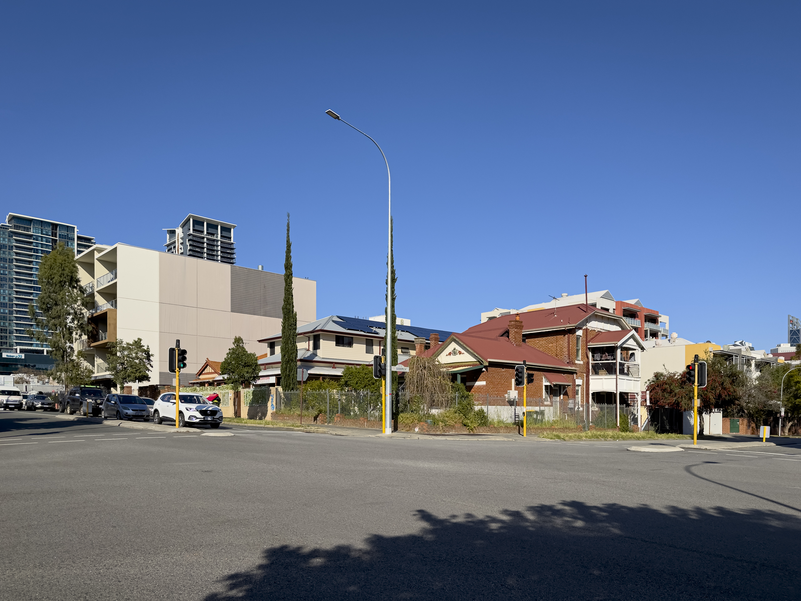 A street corner fronted by small buildings with larger buildings in the background