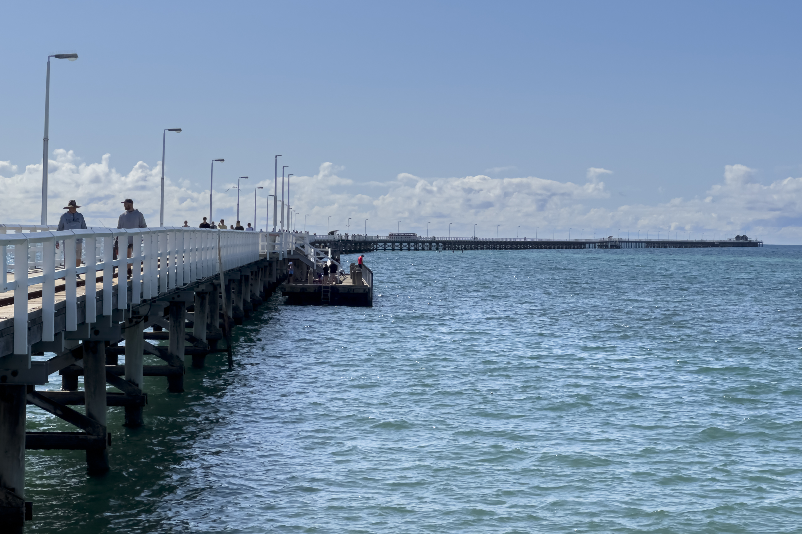 A long wooden jetty stretches out into the ocean