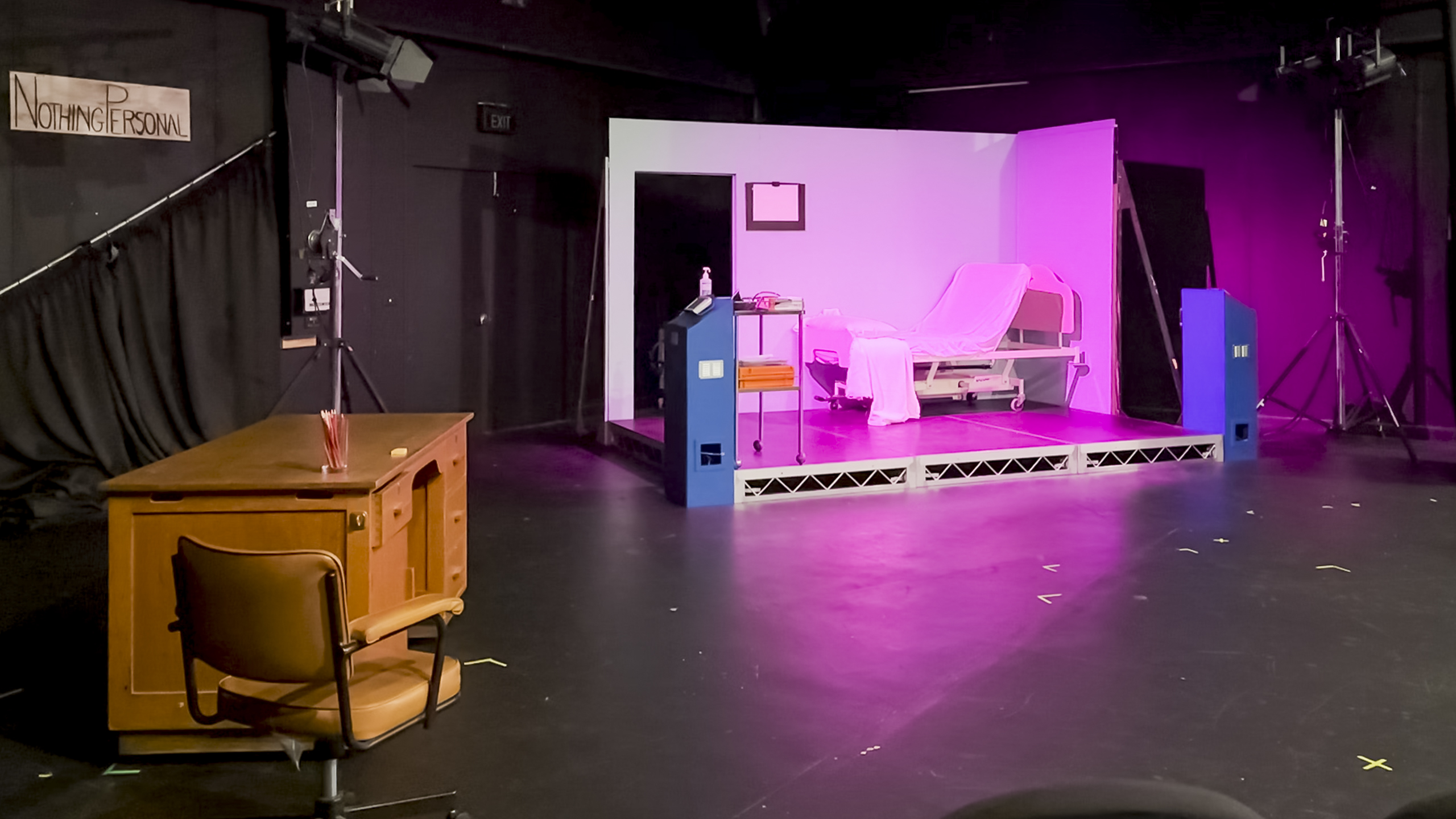 A theatre set, which is a TV studio for a show set in a hospital room. There is a bed on the 'set' and off screen is a desk