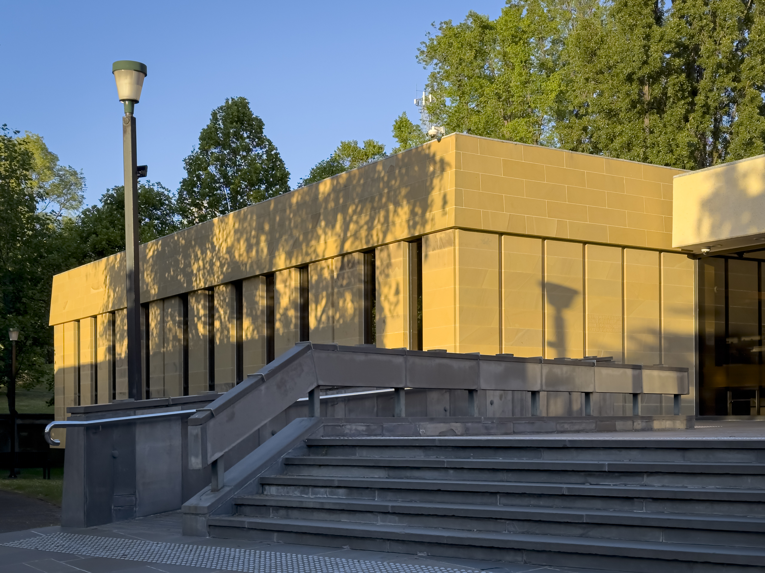 A low sandstone building glows in the morning light. There is an angled set of stairs out the front