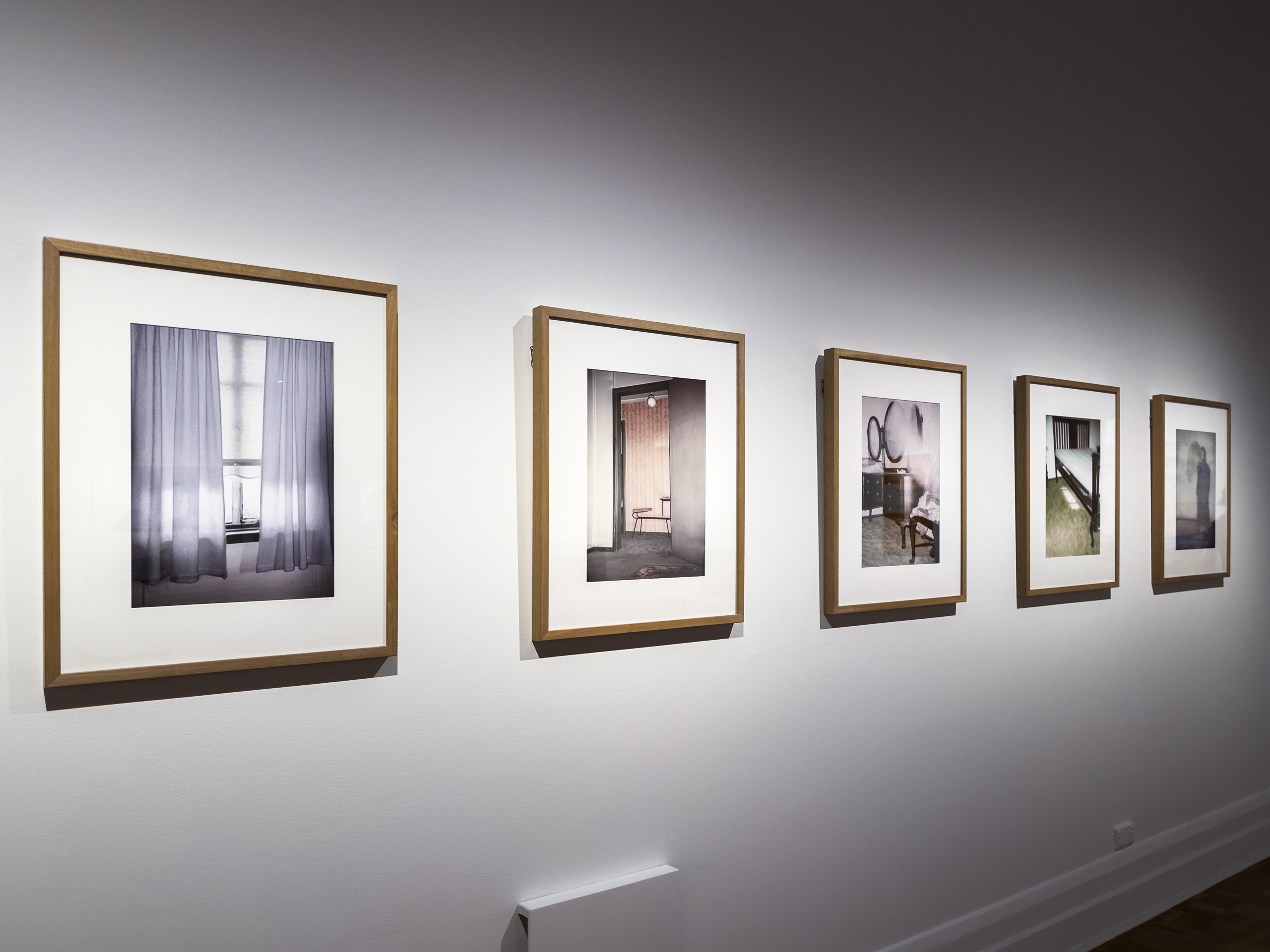 A series of framed photos of abandoned rooms on white wall