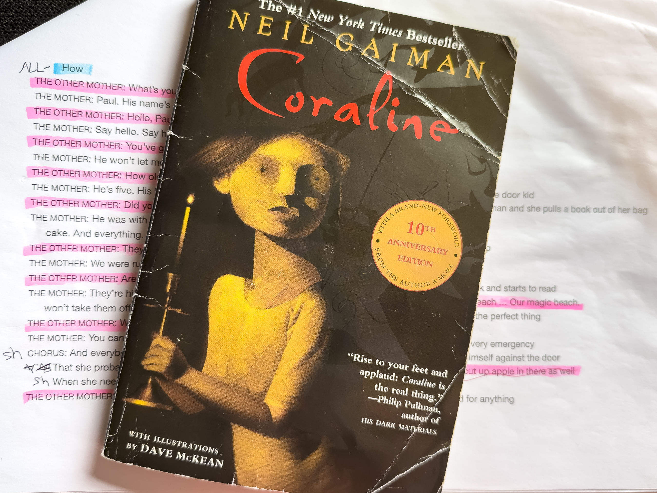 The book Coraline is sitting on top of a play script with the lines from a character called The Other Mother highlighted