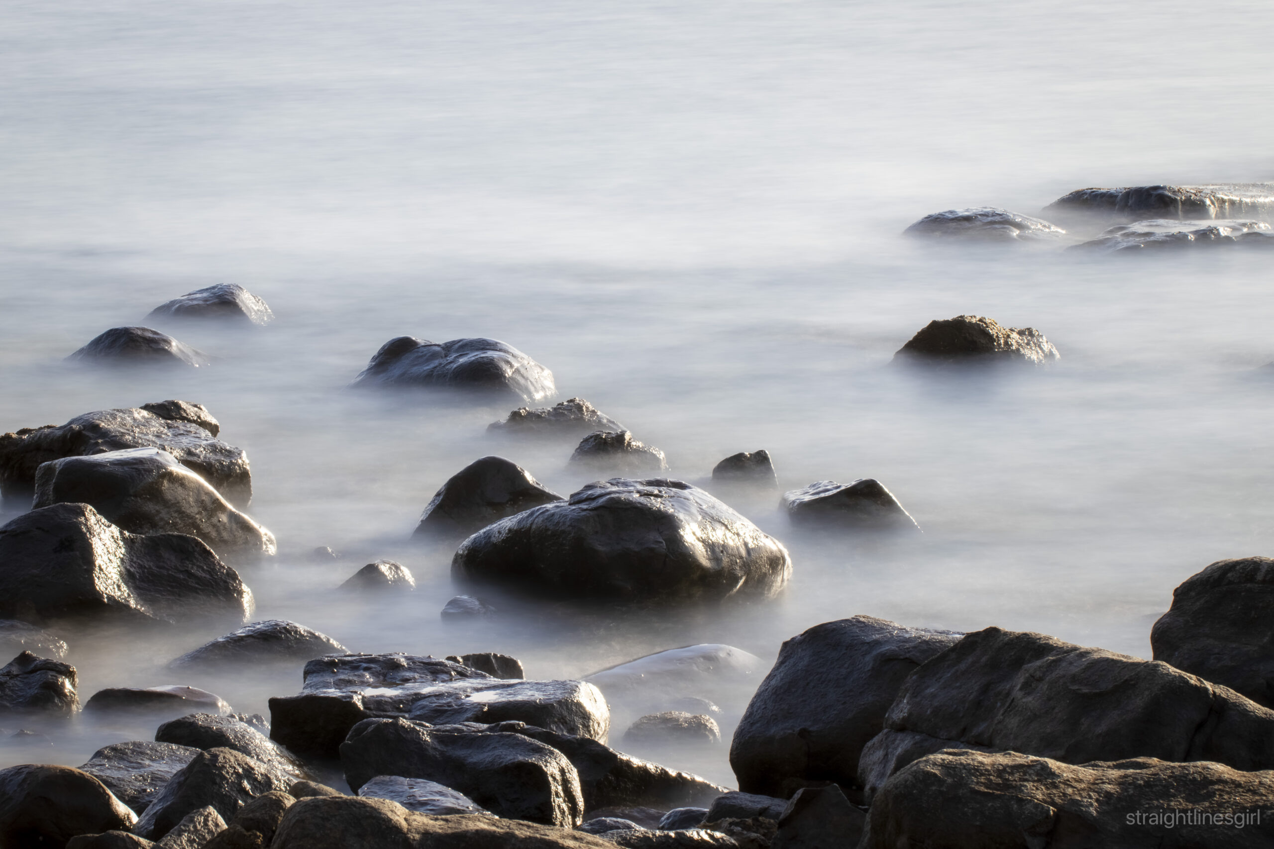 A group of rocks sitting in water that is moving gently