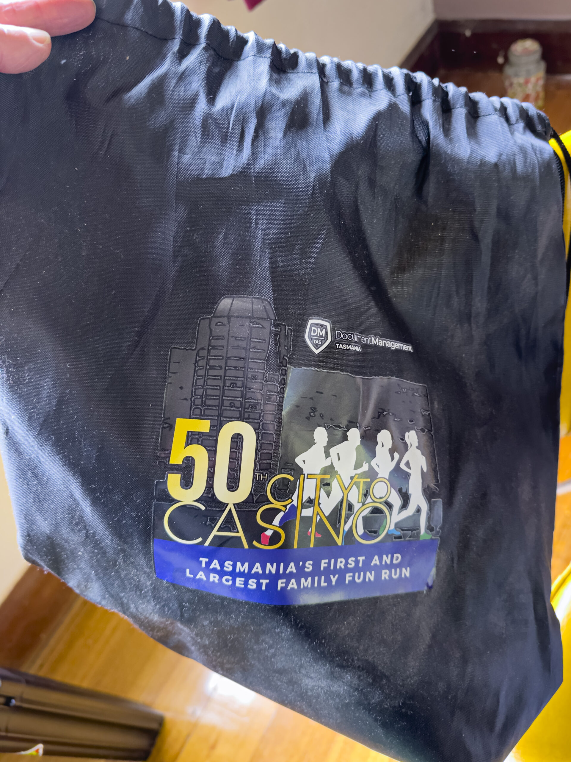 A black drawstring bag with the 50 City to Casino ad on the front