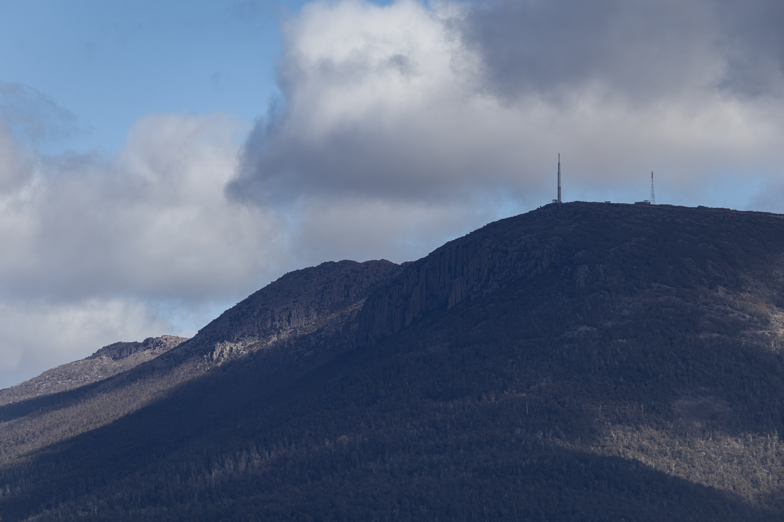 A mountain looms in the distance. There are clouds in the sky and a high tower on top of the mountain.