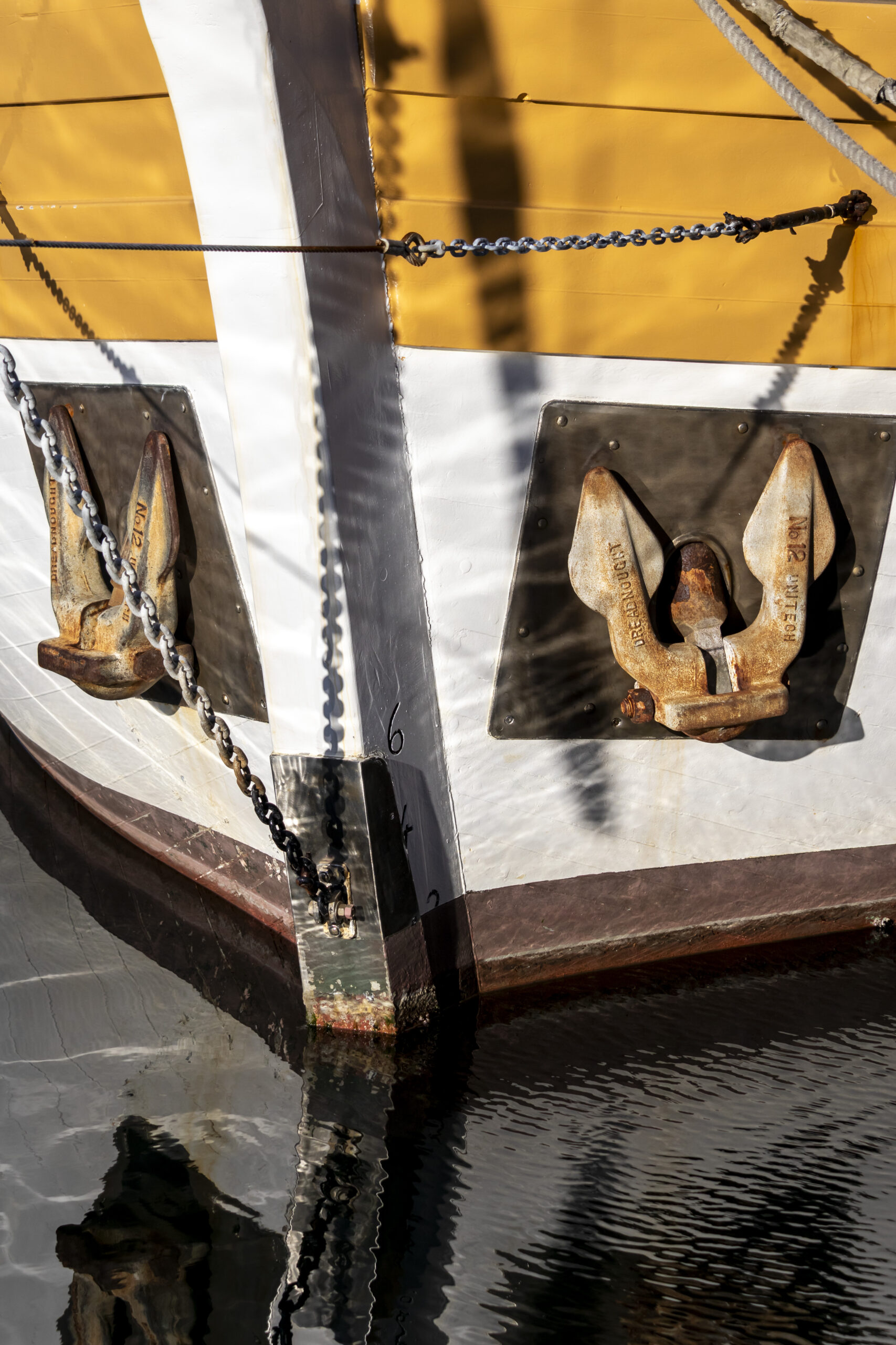 Close-up image of the bow of an old wooden boat. The water ripples are reflected onto the boat