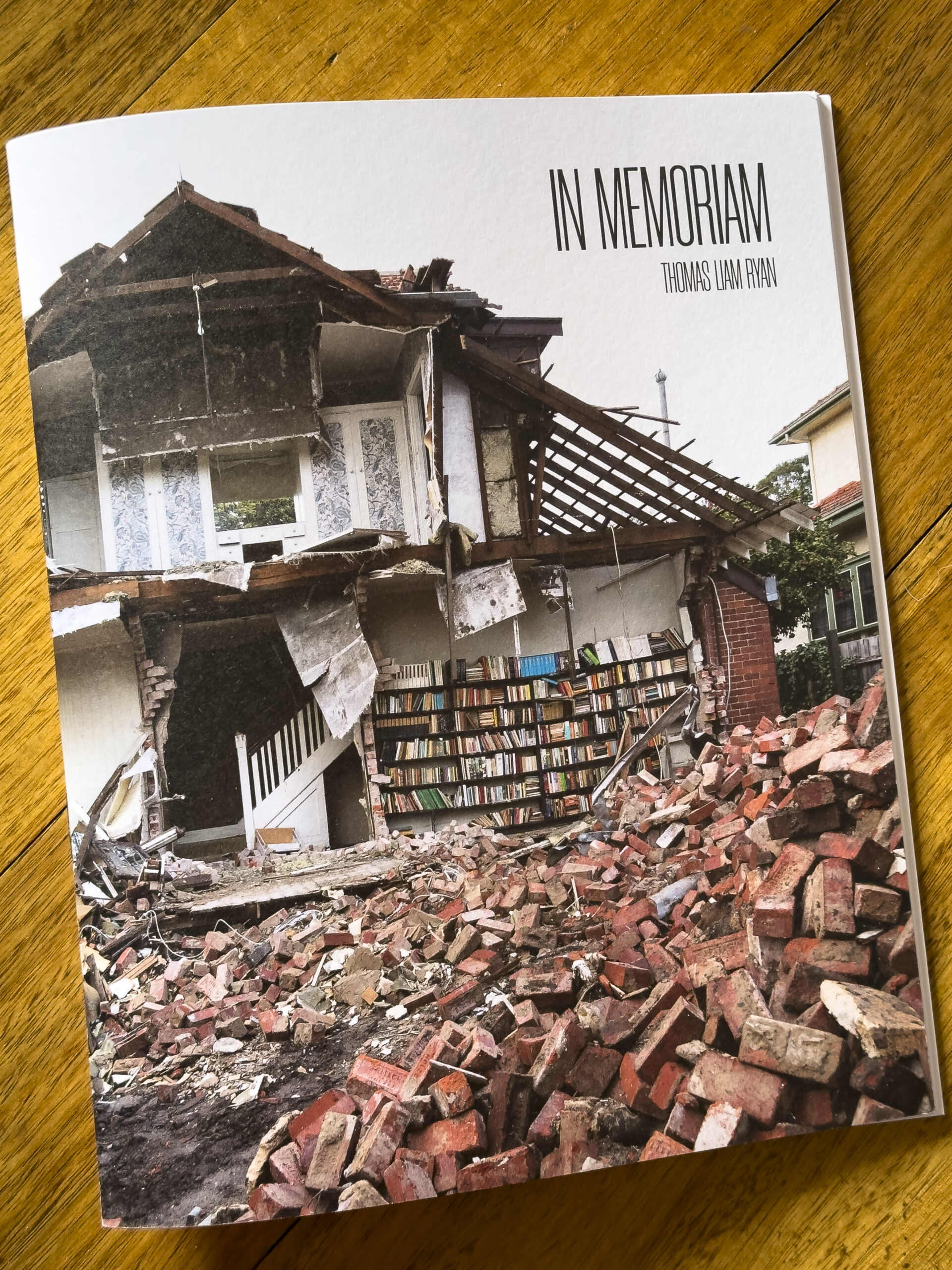 A book called In Memoriam which features a photo of a half-demolished brick house