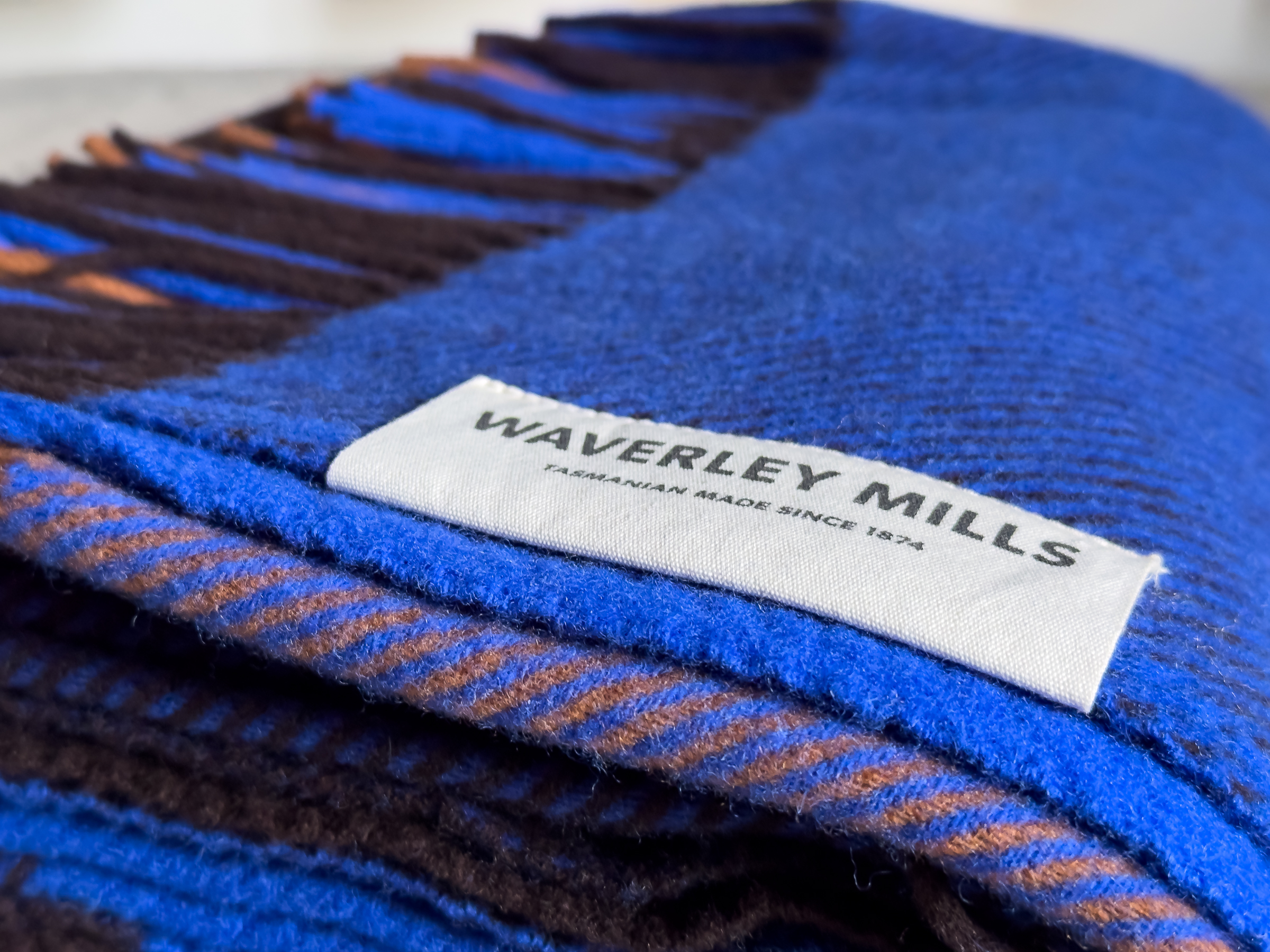 Close up of a folded blue blanket with a white tag for Waverley Mills