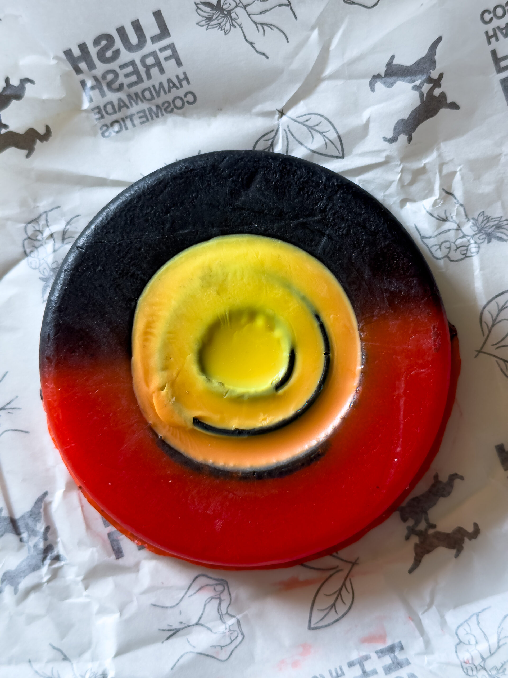 A circular bar of soap with the top segment in black, the bottom segment in red and a yellow circle in the middle representing the Australian Aboriginal flag