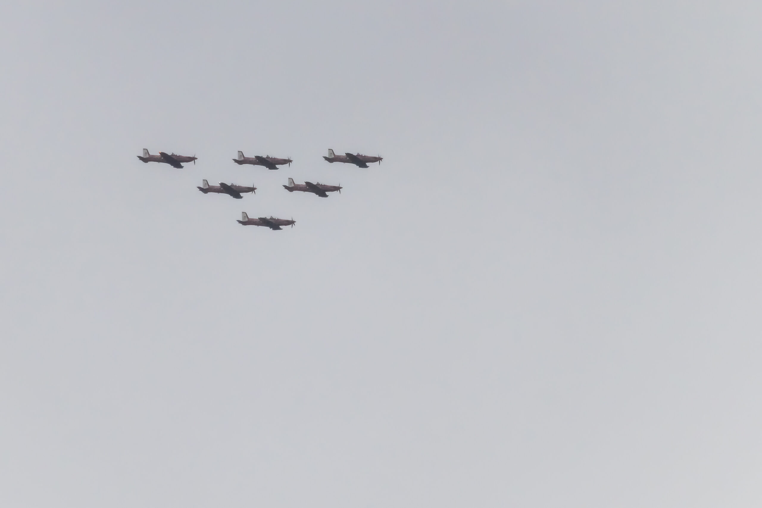 Six planes flying in a pyramid formation in a cloudy sky
