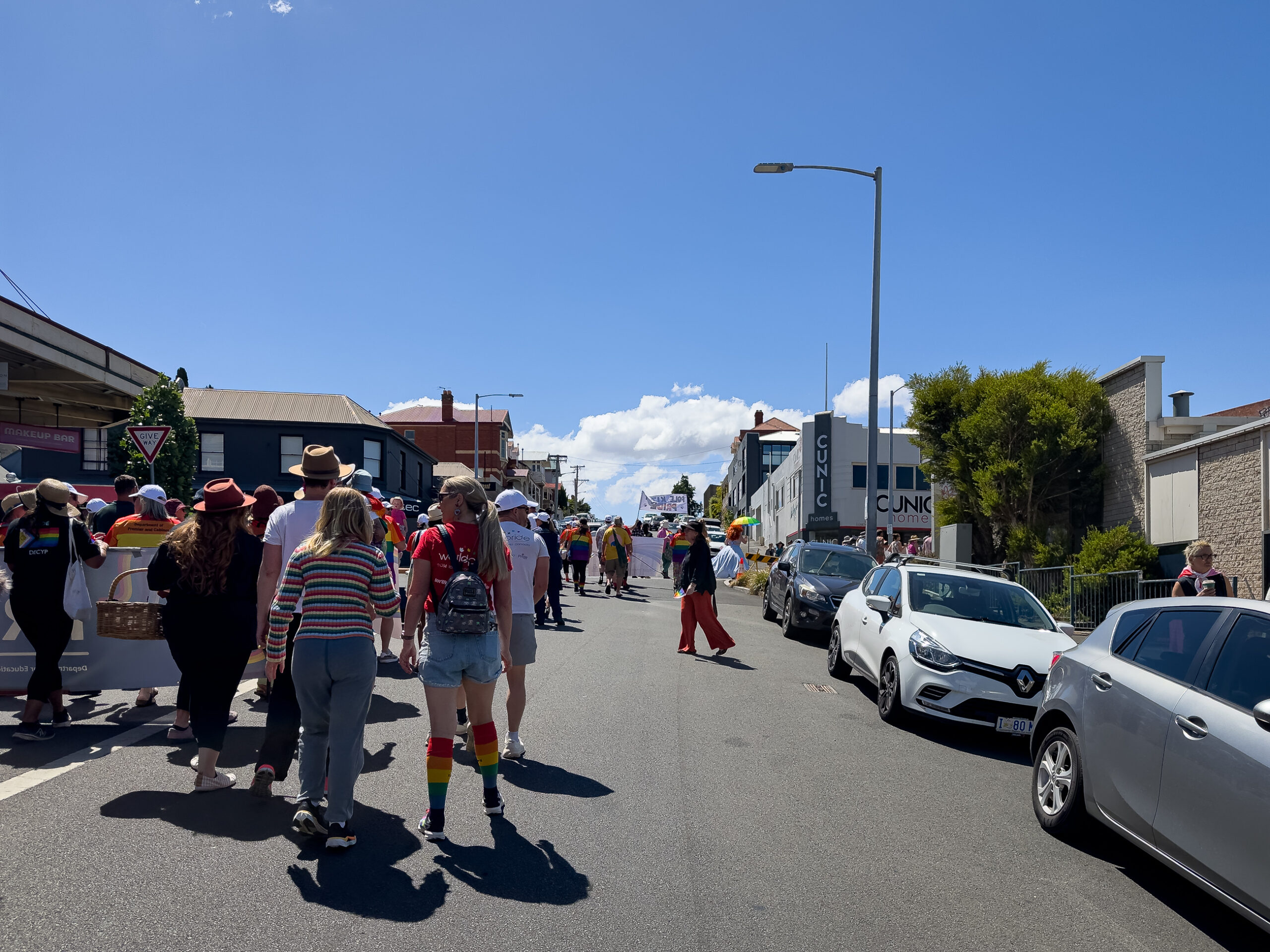 A group of people walking up a street photogaphed from behind